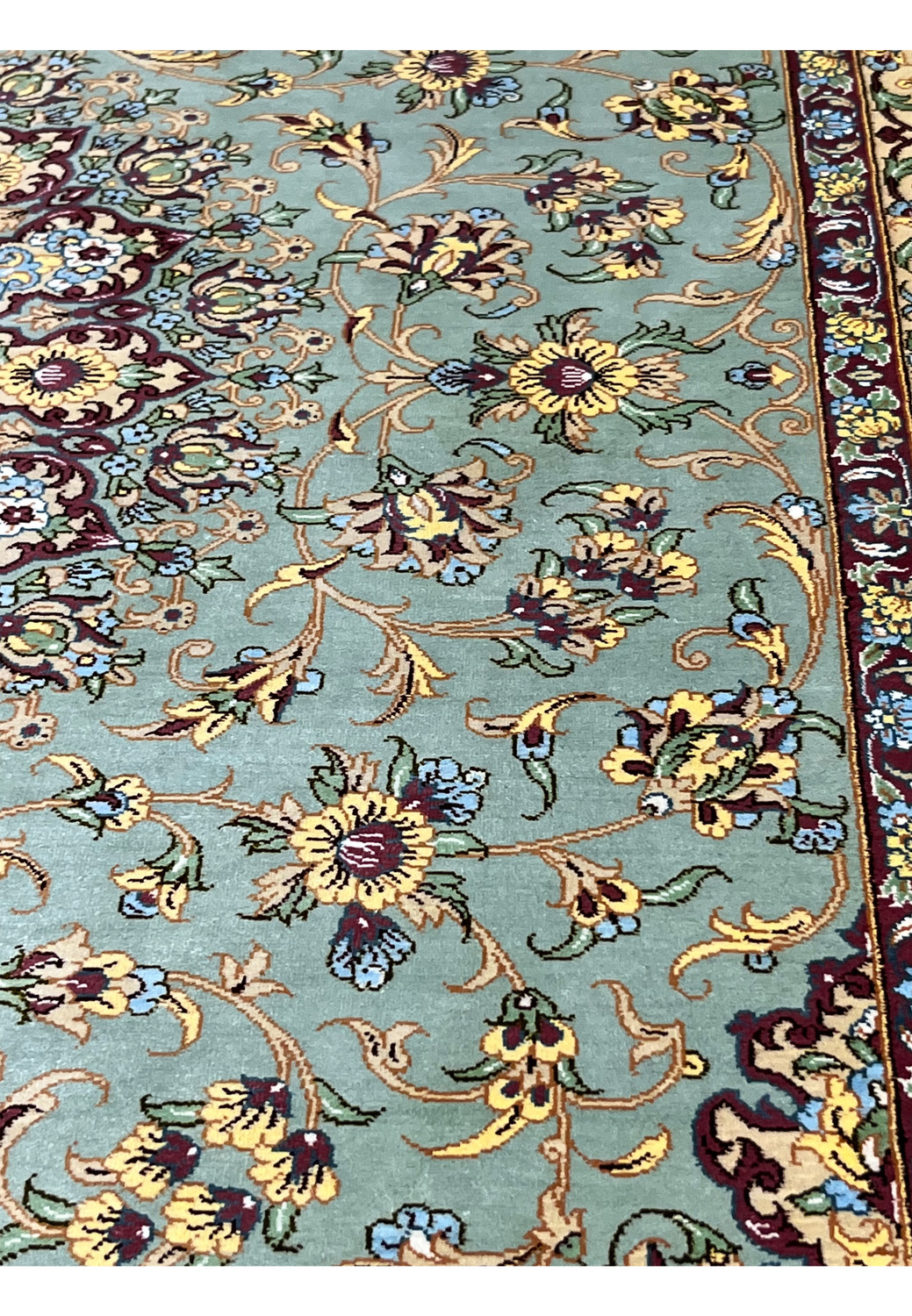 Color detail close-up of a Mirmehdi Persian Qum silk rug highlighting silk sheen, sage green field, burgundy florals, and gold accents