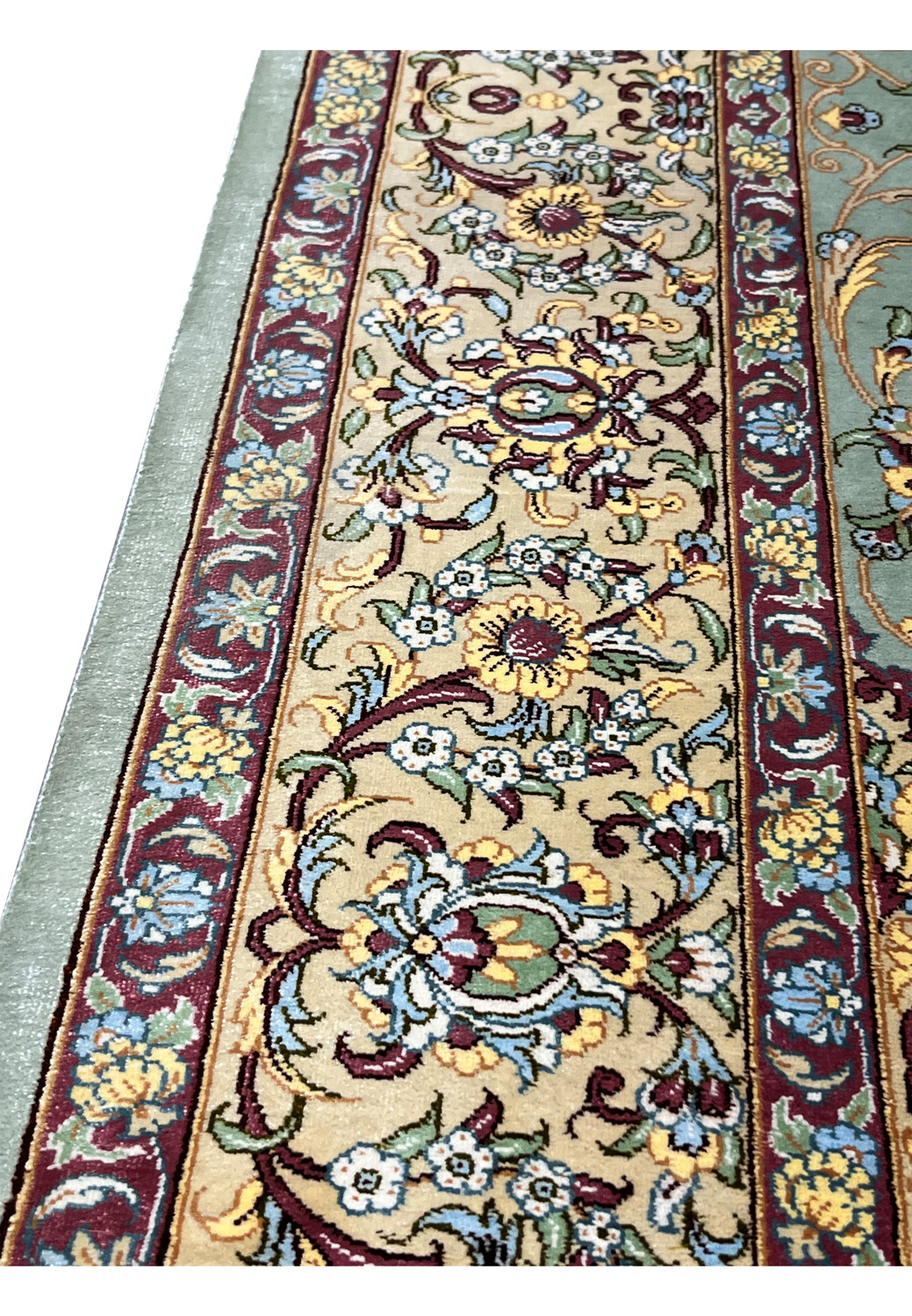 Detailed view of Persian Qum rug border with warm ivory ground, burgundy outlines, gold vines, and light blue floral motifs in pure silk