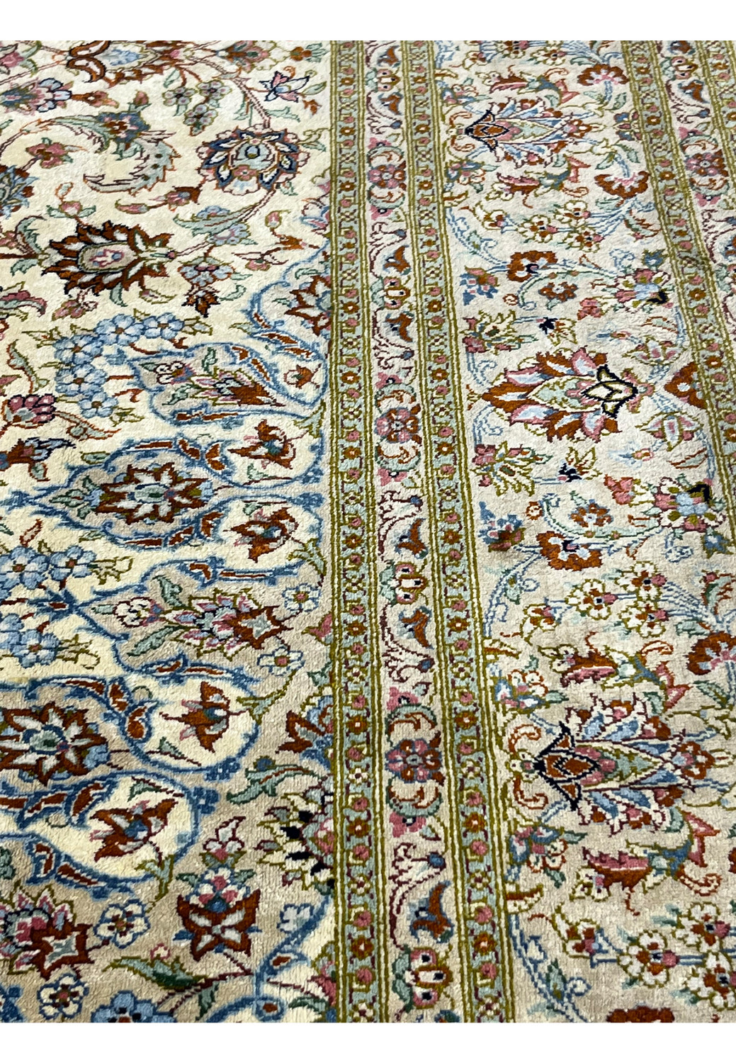 Side border detail of a signed Persian Qum silk rug highlighting intricate floral vines, layered guard borders, and precise hand-knotted silk workmanship.