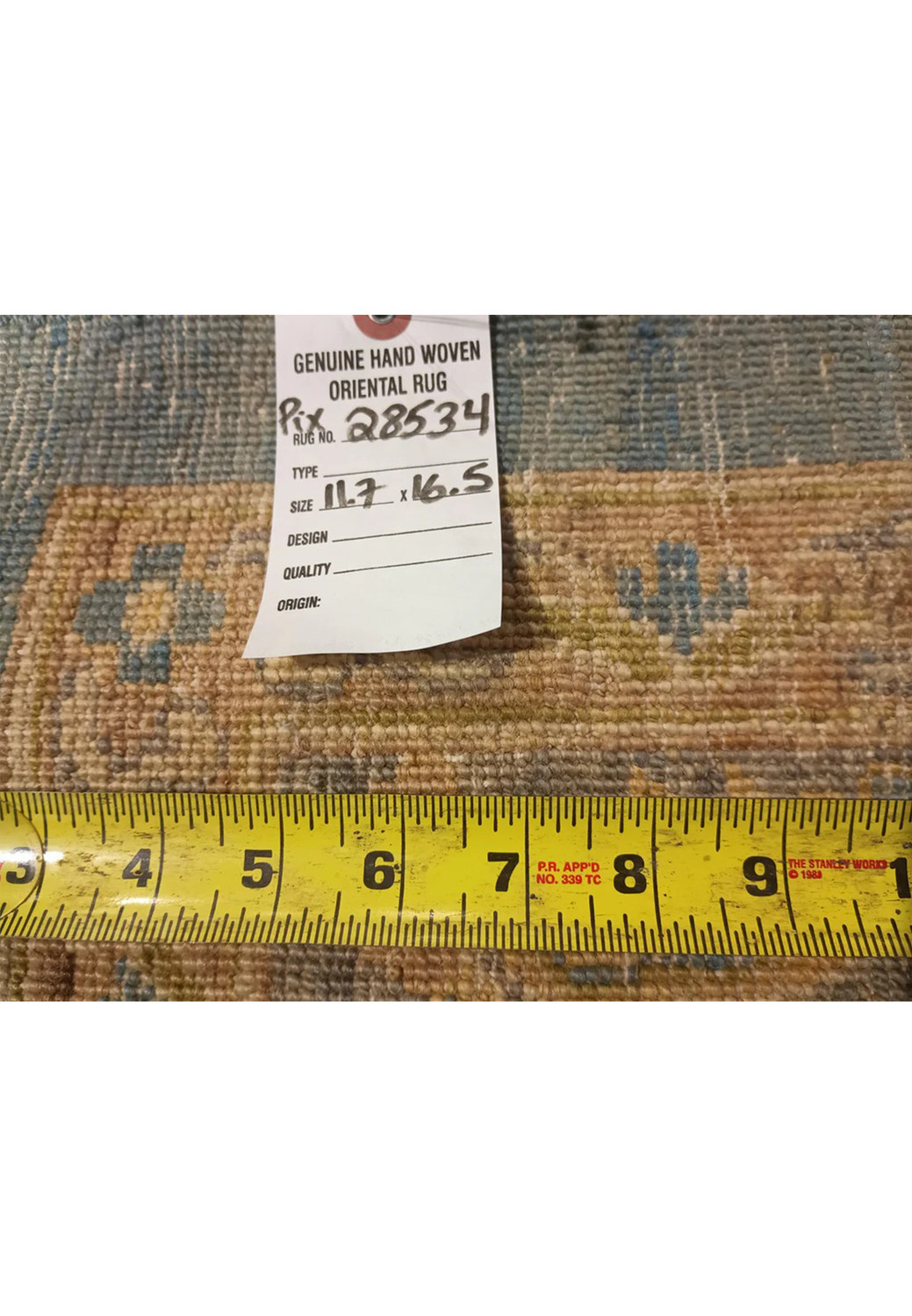 Backside of a hand knotted light blue Chobi Peshawar rug with ruler for scale, showing tight knot structure, wool foundation, and precise craftsmanship