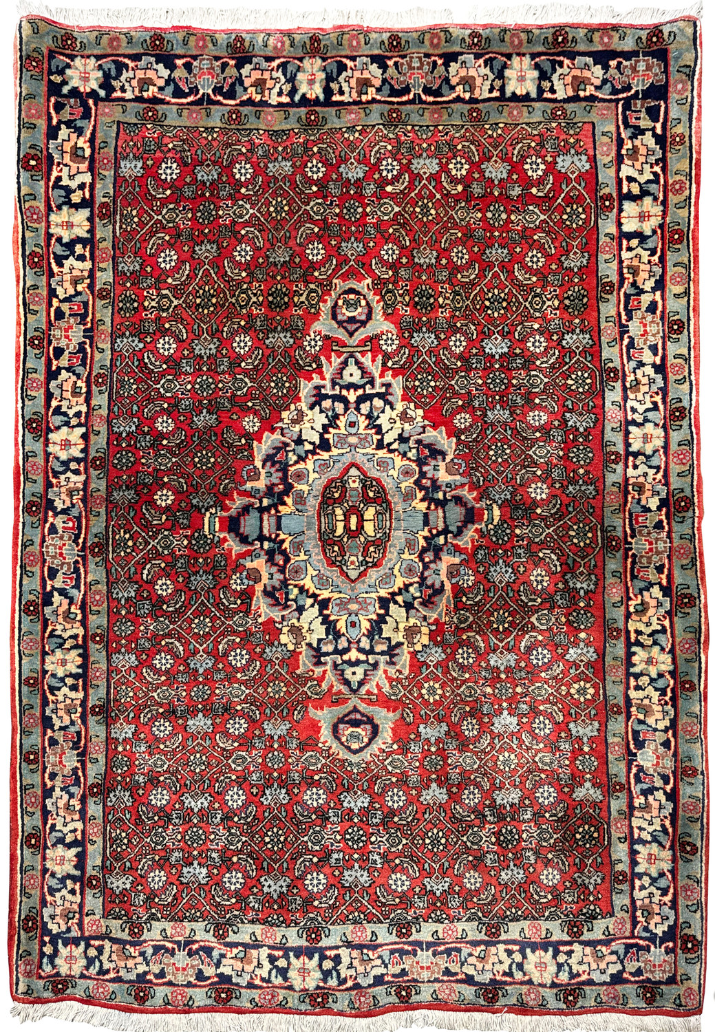 Straight-on view of a hand-knotted Persian Sarough rug showing brick red field, layered floral rosette medallion, and classic navy framed borders