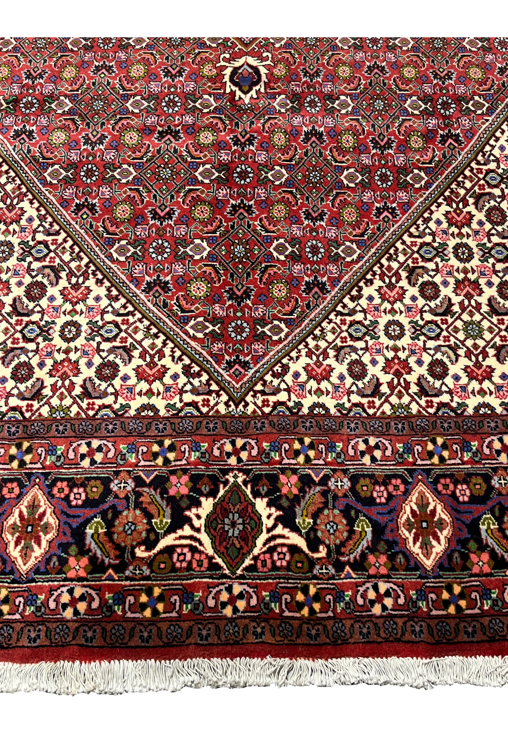 Lower border of Persian Bijar rug displaying dense floral motifs, rich red tones, navy accents, and clean hand knotted execution
