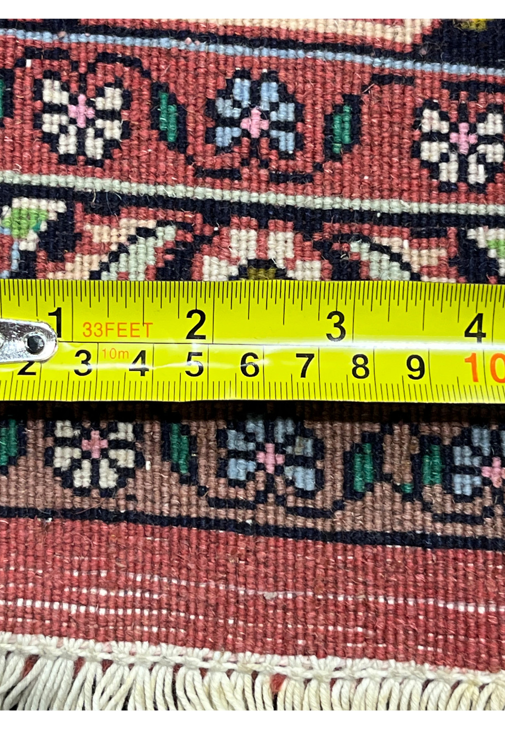 Close-up of Persian Bijar rug back with ruler measuring knots per inch, emphasizing high knot count