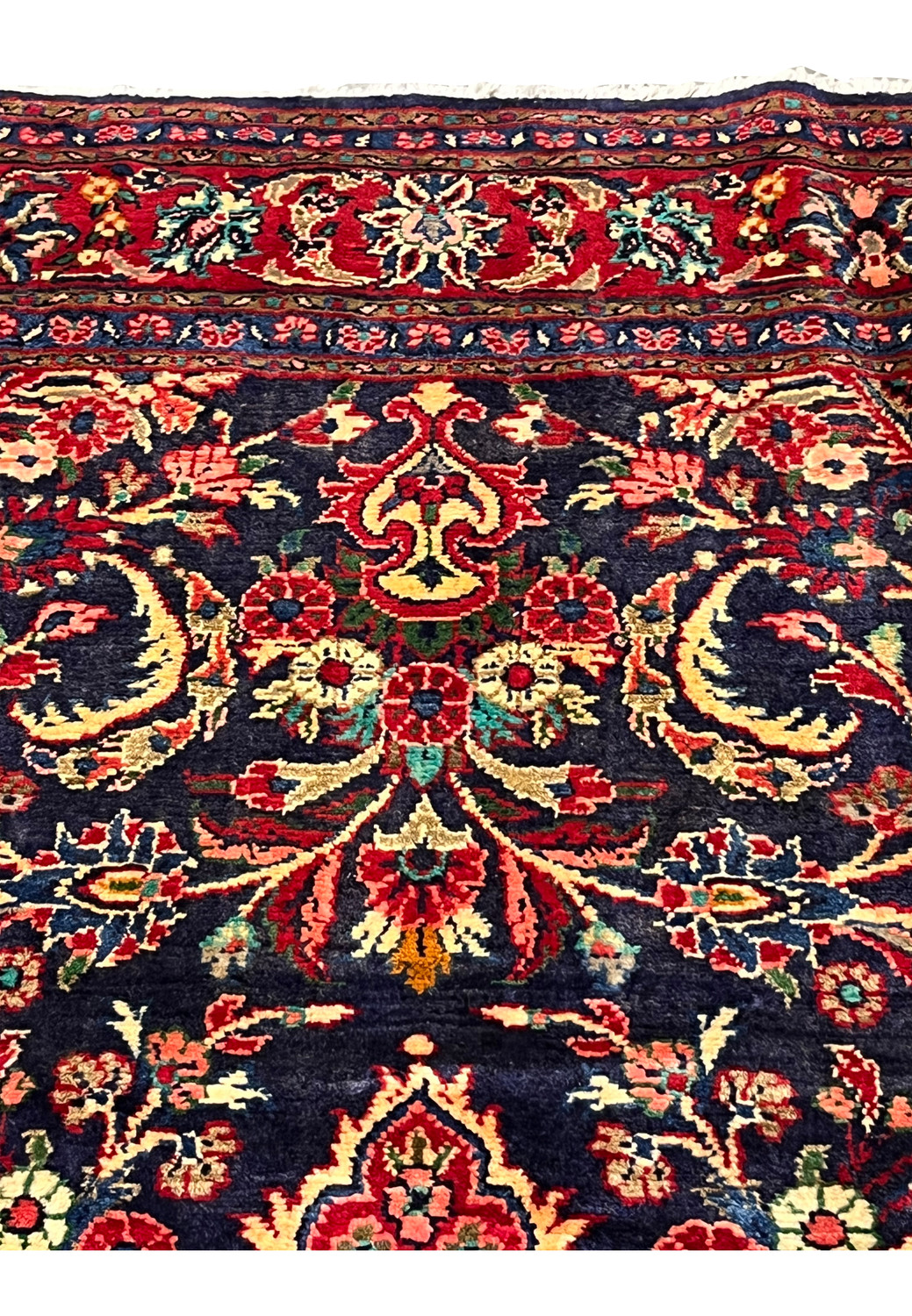 Floral motif detail on navy field showing scrolling leaves, rosettes, ivory accents, and classic Persian botanical design woven in wool