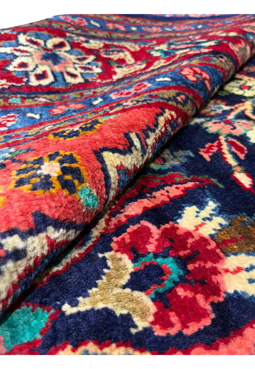 Rolled edge view of Persian Mahal rug revealing thick wool pile, sturdy foundation, and vibrant red and blue border colors