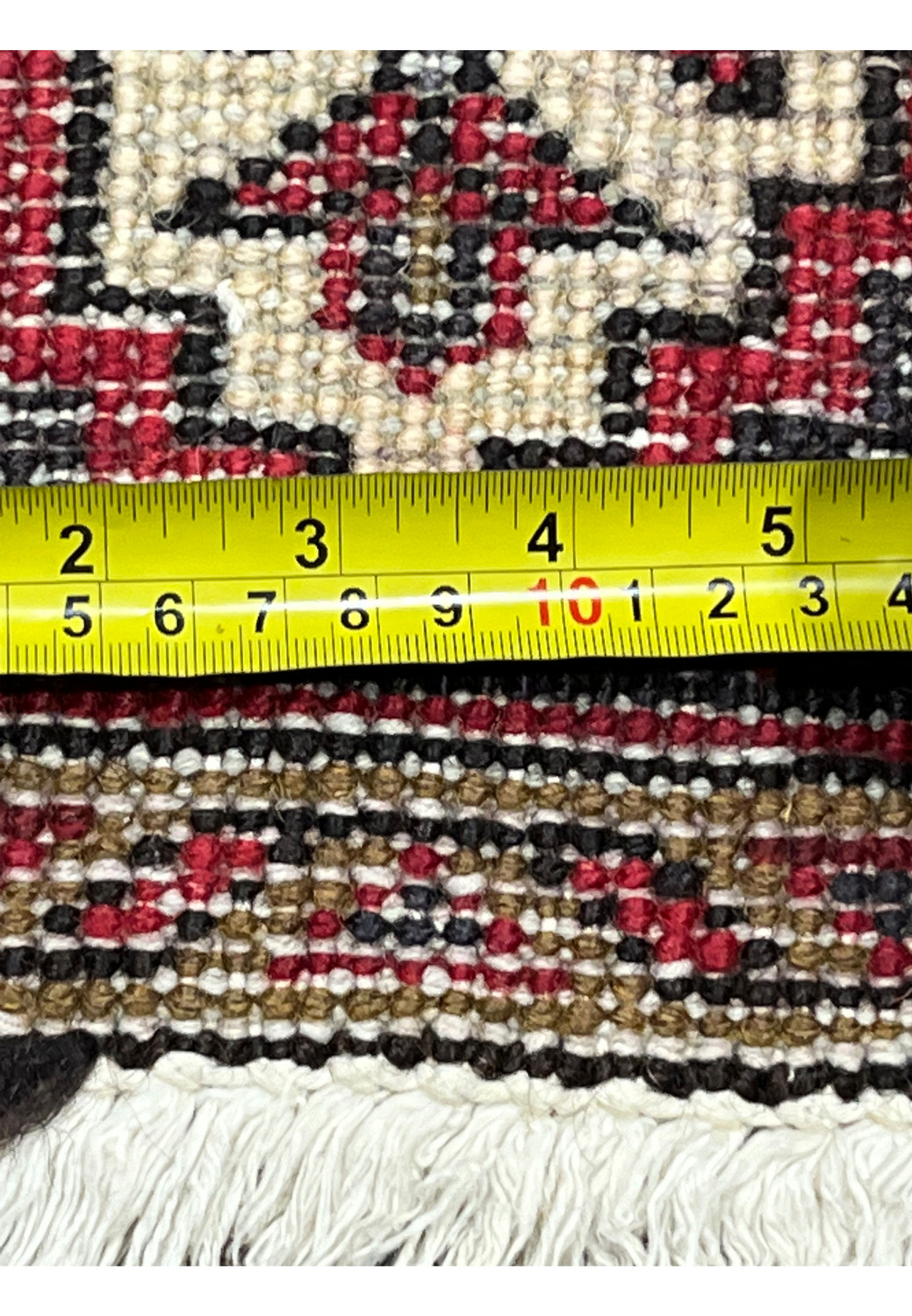 Zoomed ruler measurement on rug back displaying fine knot count, compact weave and precise craftsmanship confirming authentic Persian hand knotting