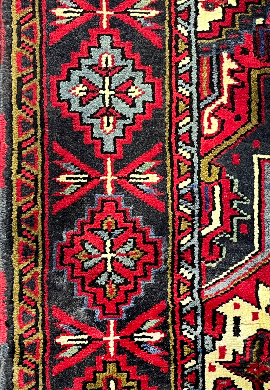 Macro border closeup highlighting bold tribal medallions, serrated motifs and contrasting outlines with thick wool pile and high definition texture