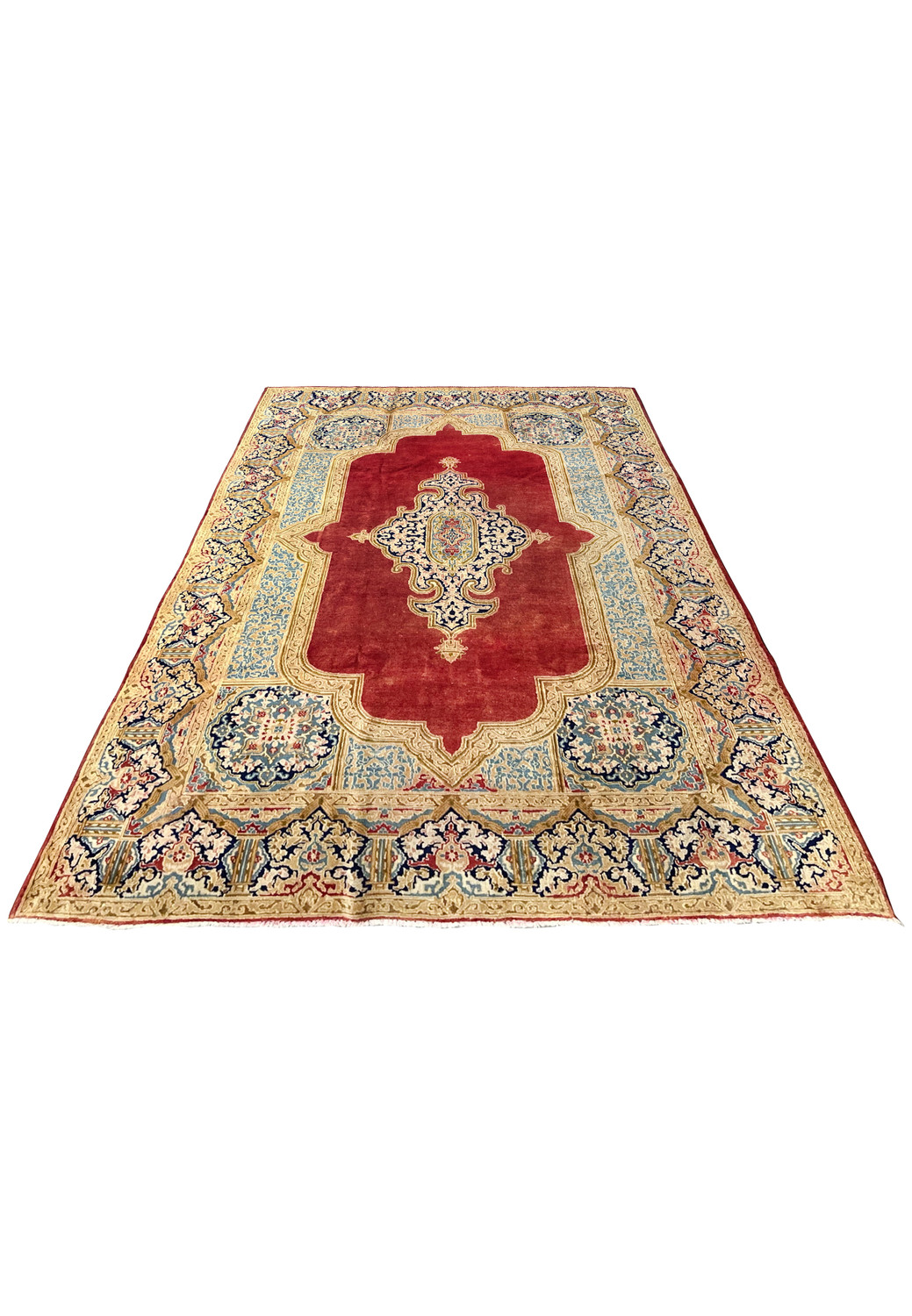 Laid down angle of vintage Persian Kerman rug showing soft wear patina floral field ivory border sky blue panels wool pile texture