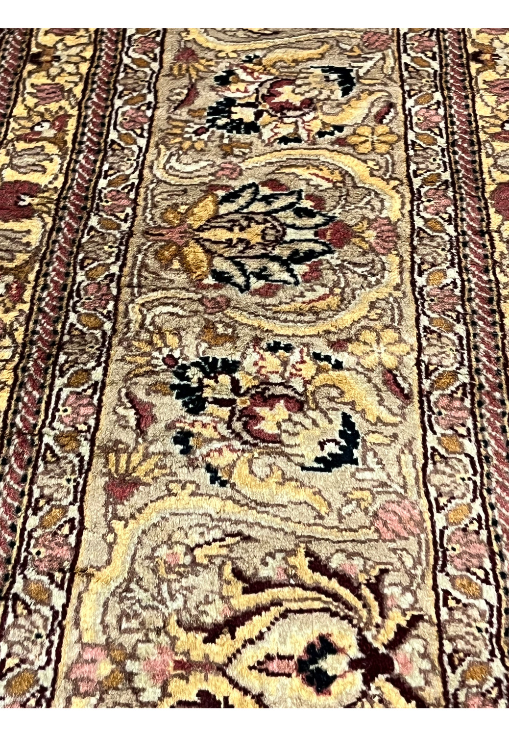 Closeup of Agra rug border with floral cartouches, beige tan ground, burgundy and gold accents, showing detailed hand knotted wool texture