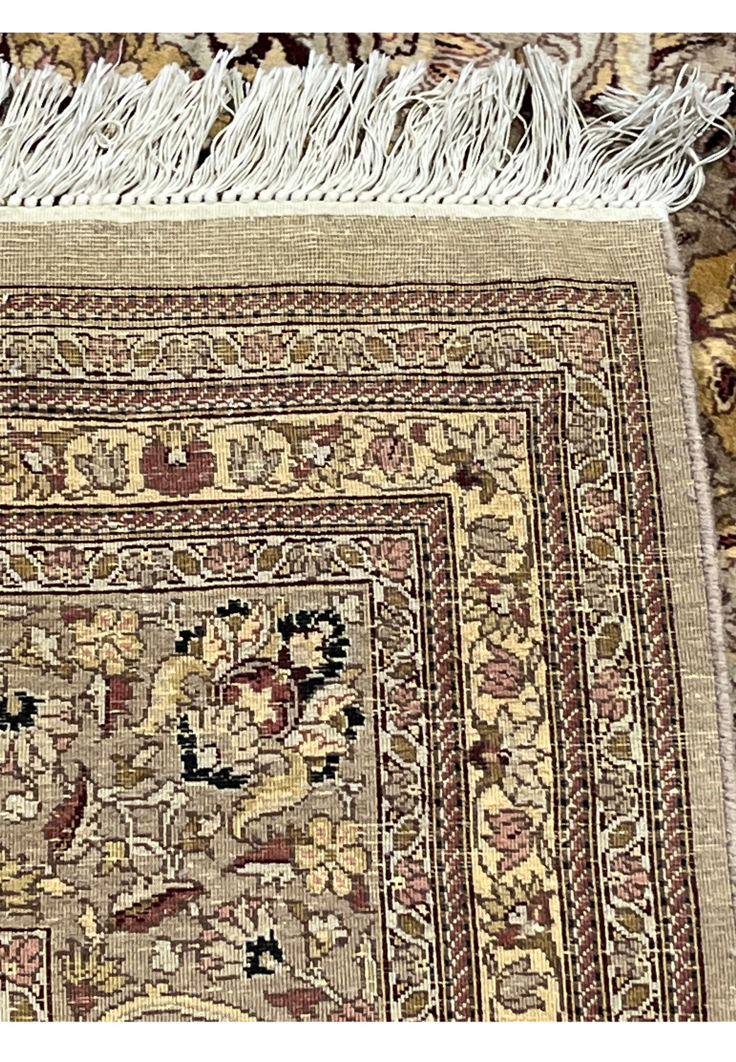 Backside view of hand knotted Agra rug displaying tight knot structure, natural wool foundation, fringe, and authentic handmade craftsmanship