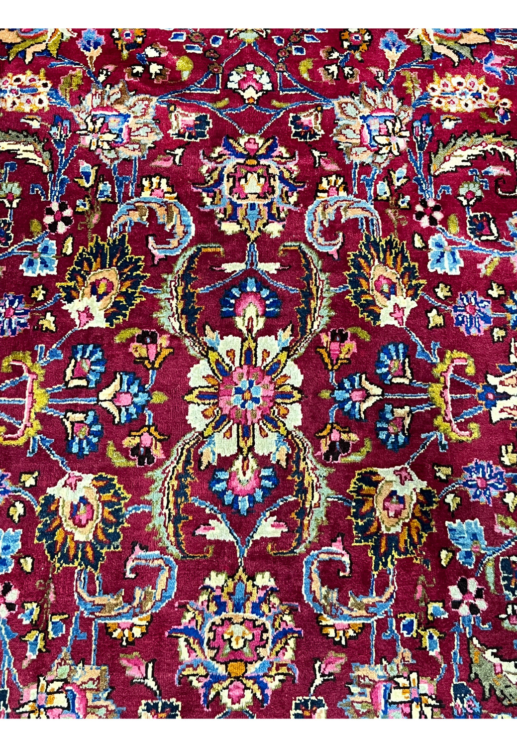 Closeup of central medallion with floral rosettes, navy outlines, and multicolor highlights woven in fine wool.