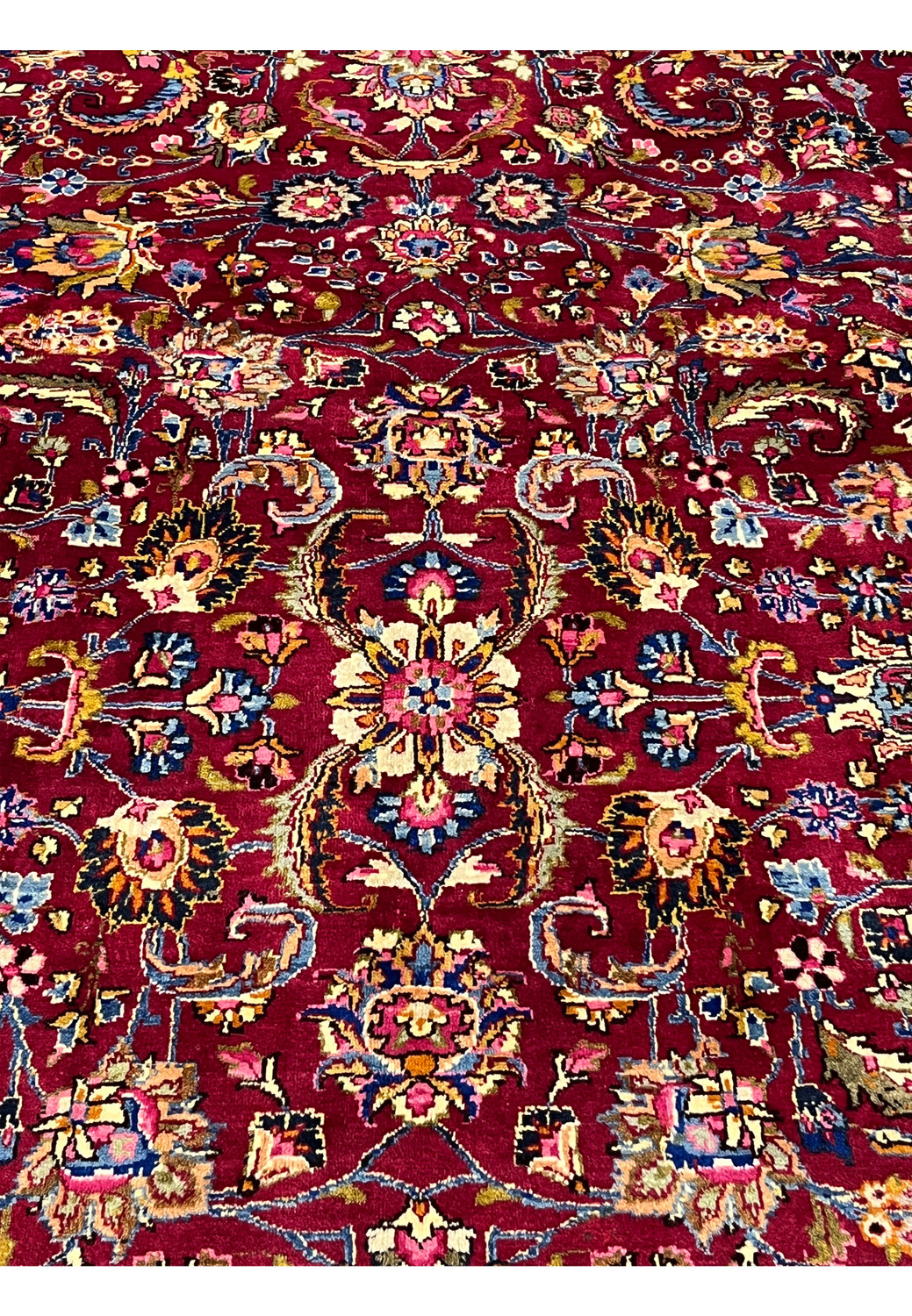 Pattern detail of Persian Mashad rug highlighting repeating floral medallions, vine scrolls, and balanced symmetry across the red field.
