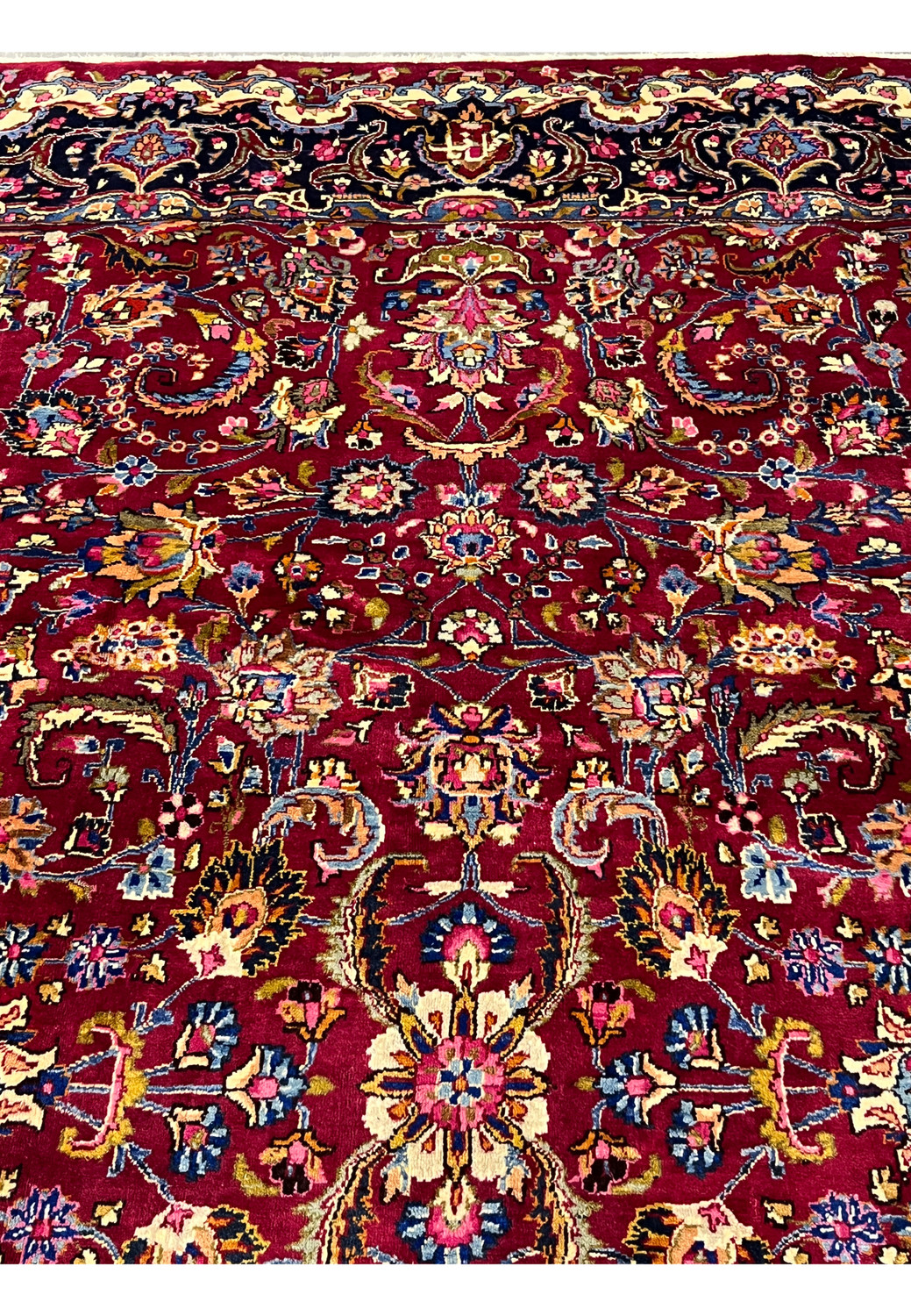 Close-up of floral motifs and scrolling vine patterns on 8x11 Persian Mashad rug, showing dense wool pile, vibrant reds, blues, and fine knot clarity