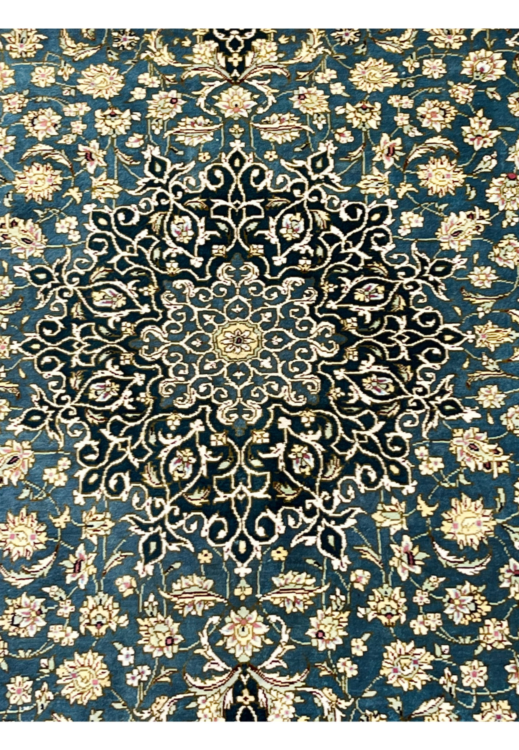 Central medallion close up with navy and ivory arabesques and floral silk detailing on deep teal field