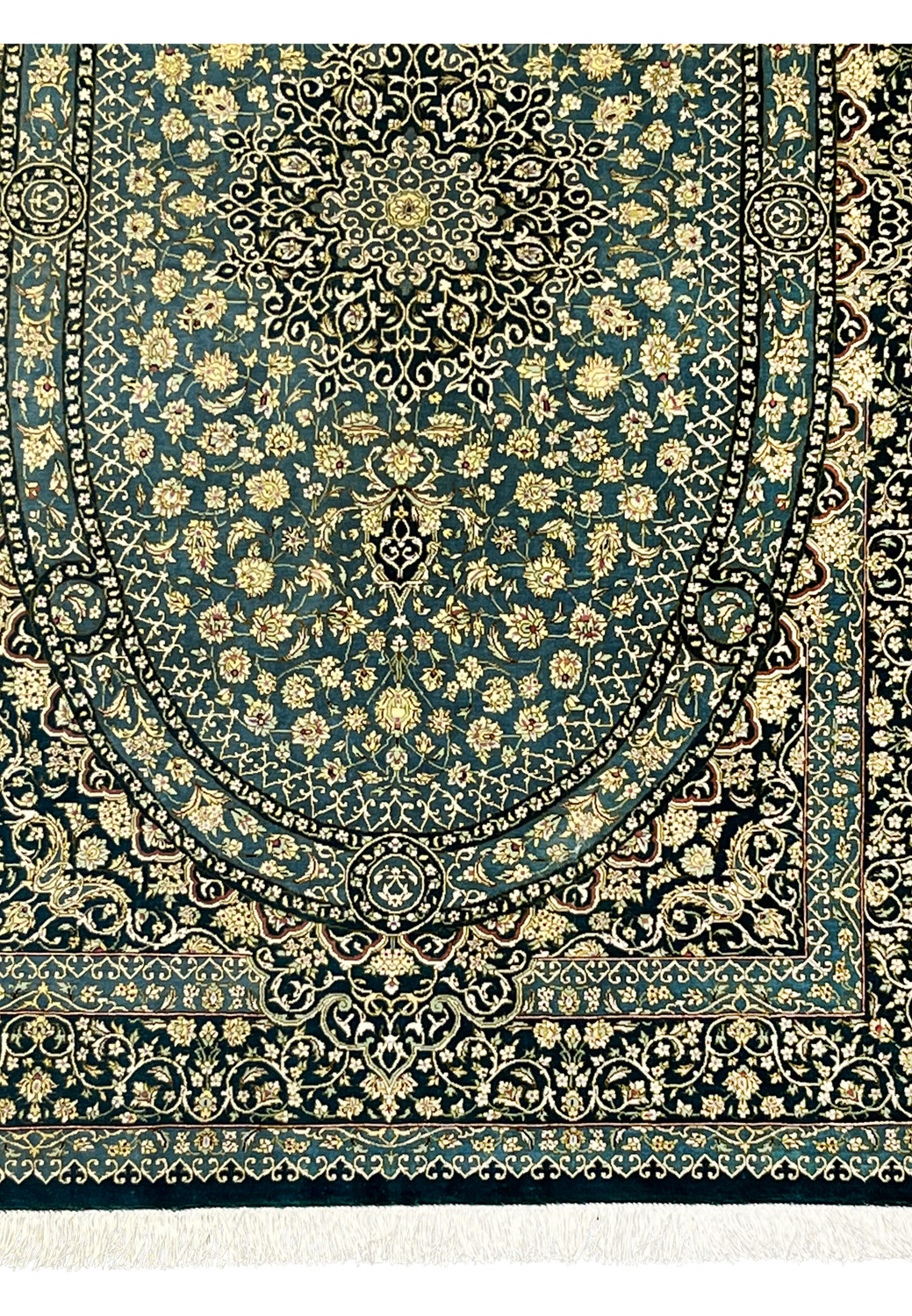 Lower section of silk Qum rug showing oval medallion base, dense florals and navy outlines with luminous teal silk background
