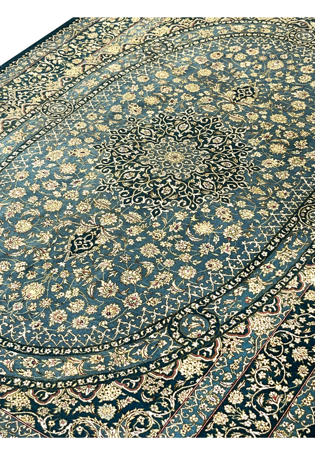 Angled perspective of signed Darakhshan silk rug highlighting oval medallion, intricate floral field and reflective silk sheen under light