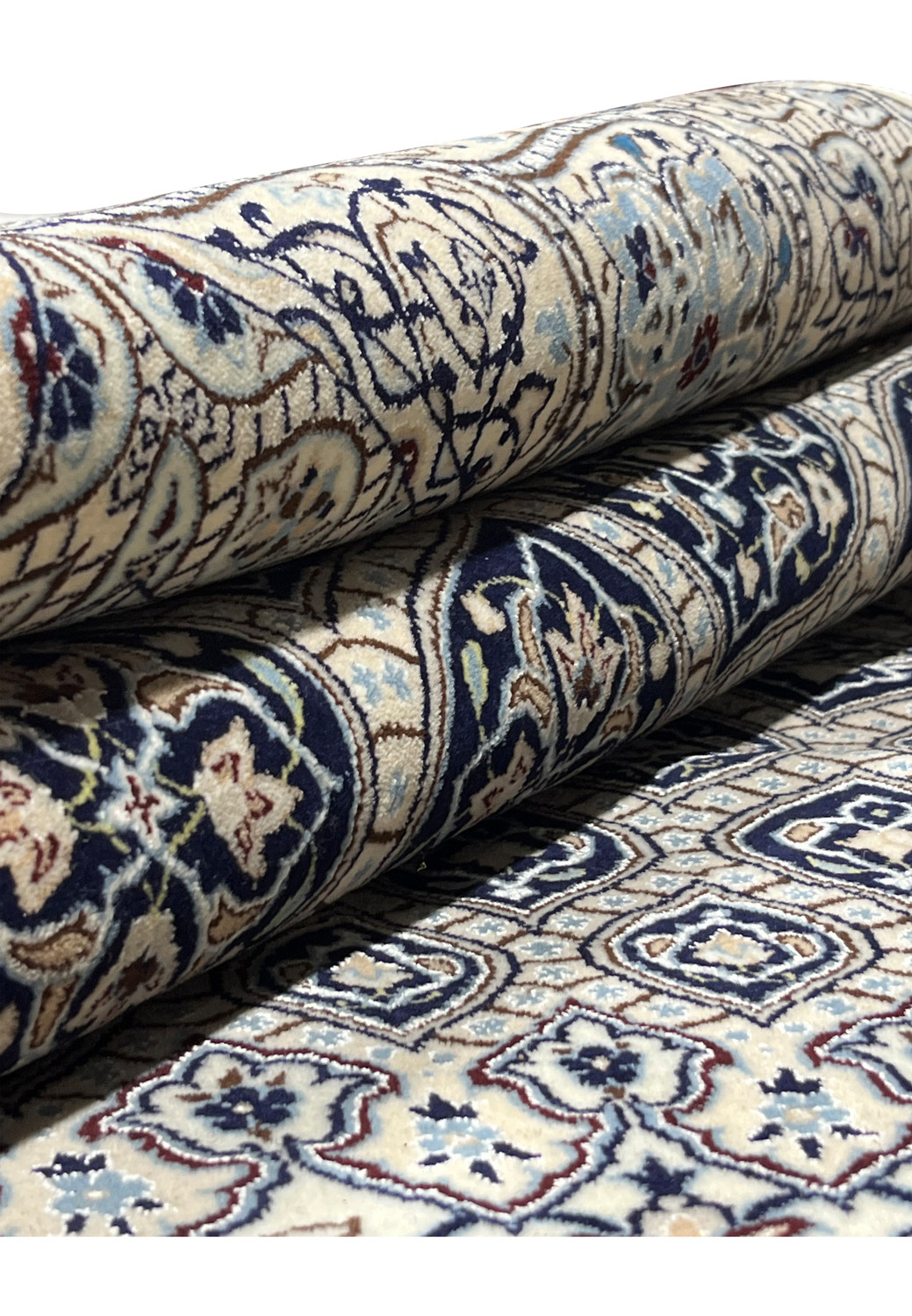 Rolled 6'9 x 10 Persian Nain Habibian 6 LA Kork and silk rug showing ivory field navy Gombadi dome pattern and tight pile.