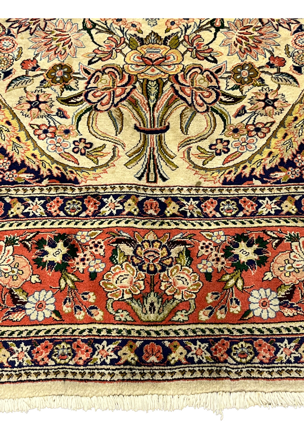 Lower field detail of Persian Bijar rug showing floral bouquets navy corner and coral medallion edge
