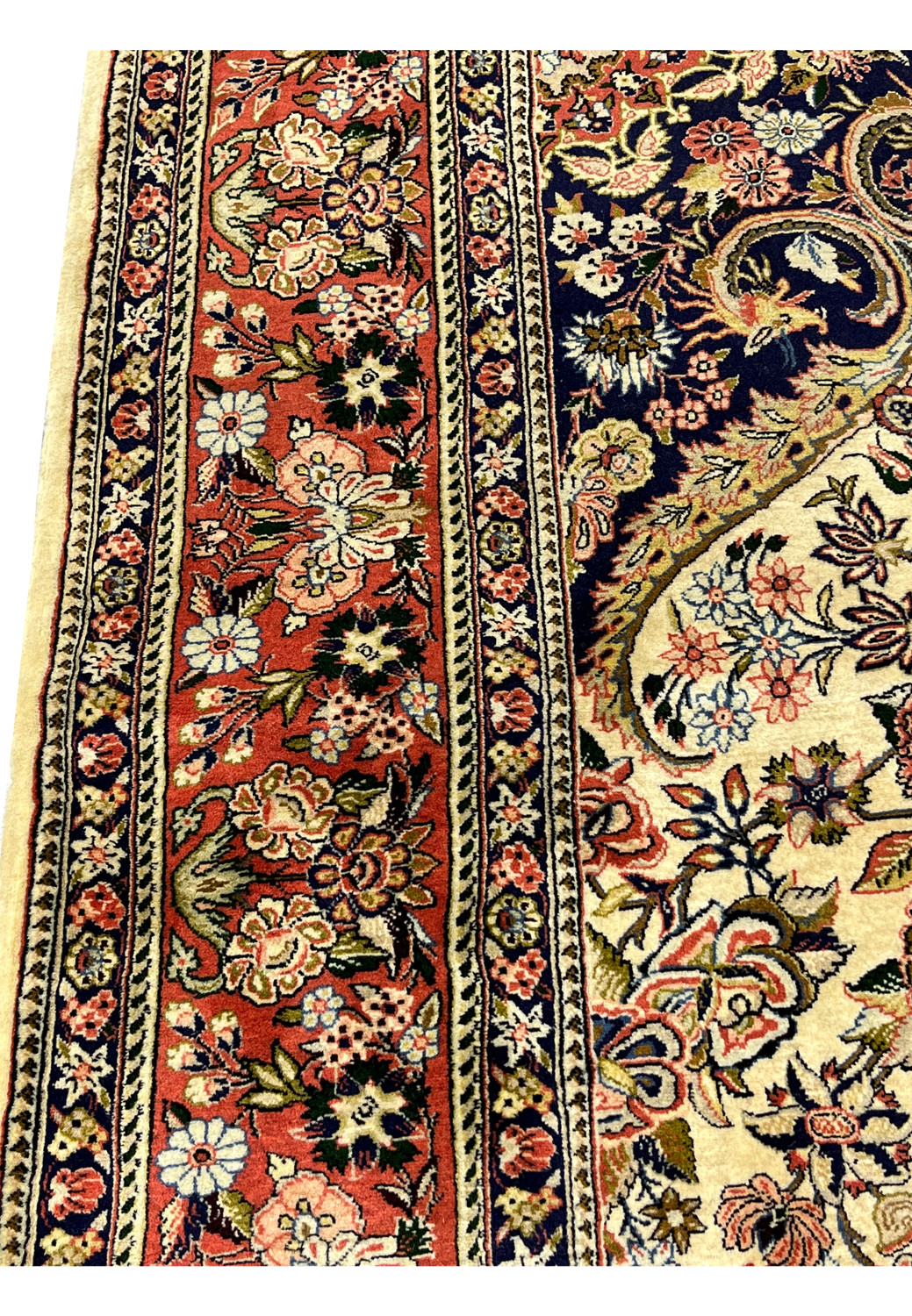 Closeup of wide coral border on Persian Bijar rug with scrolling vines palmettes and multicolor blossoms