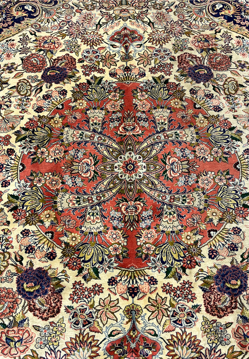 Closeup of coral red central medallion on Persian Bijar rug with symmetrical floral sprays and fine detailing