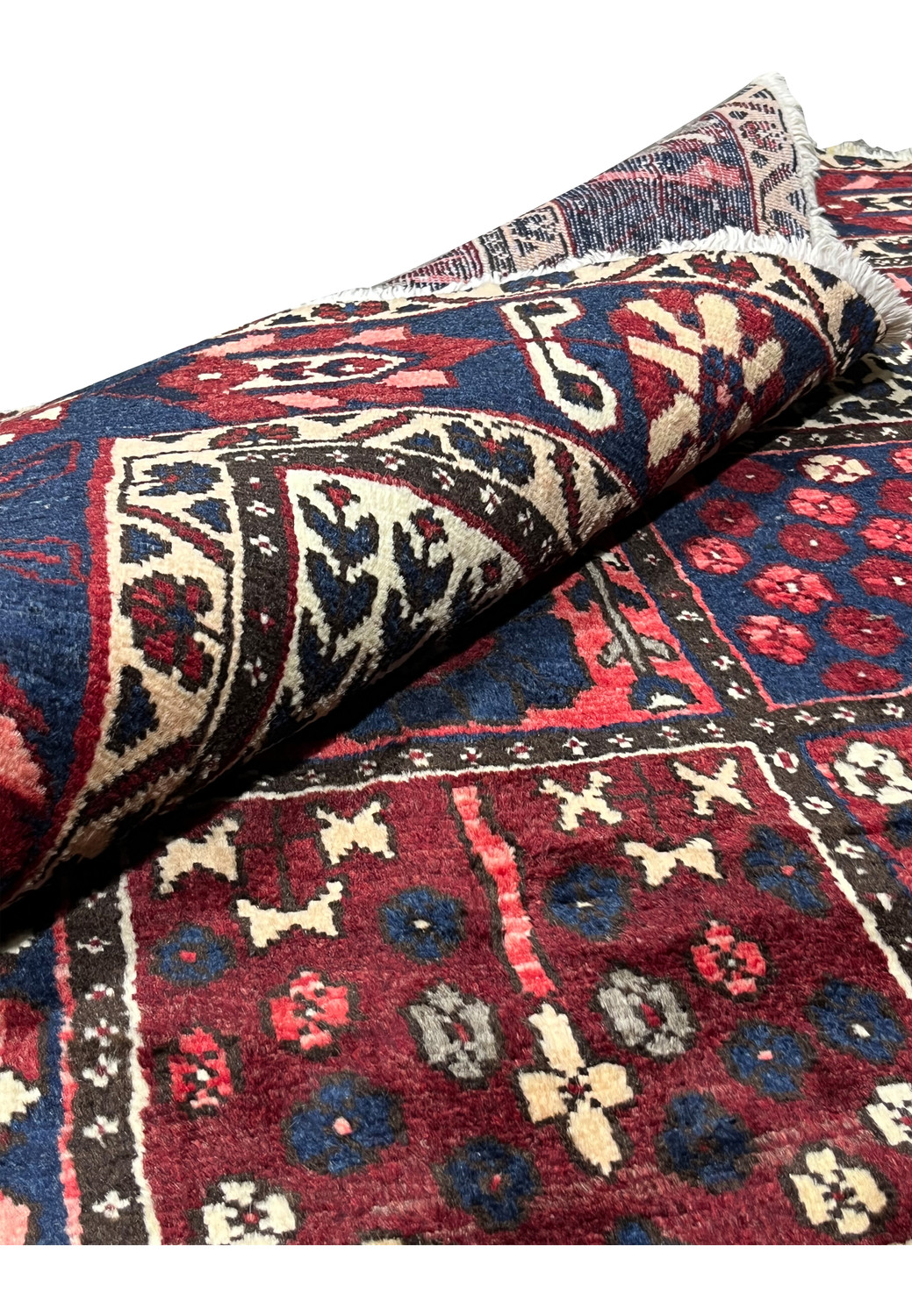 7x10 Persian Bakhtiari rug partially rolled showing wool pile and cotton foundation construction