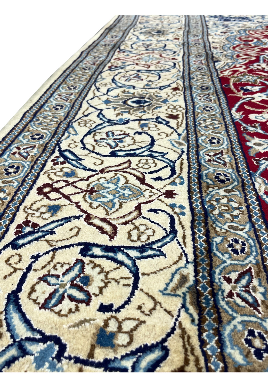 Border close-up of Persian Nain rug highlighting ivory ground, scrolling vines, and navy floral elements