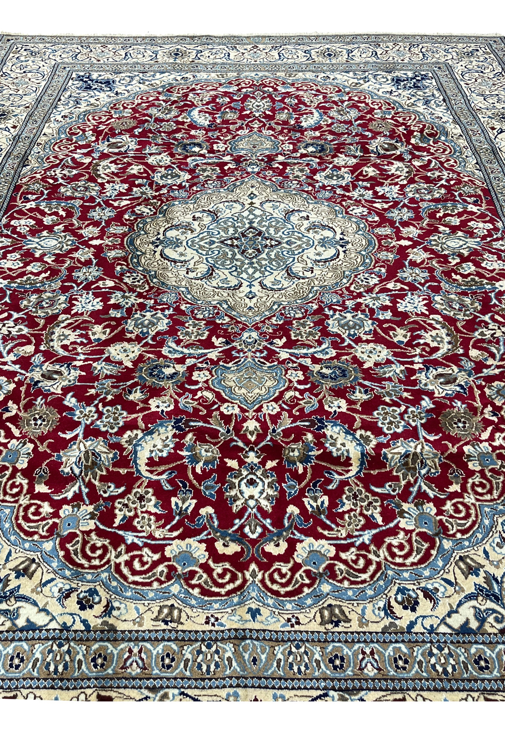 Midfield detail of red Persian Nain rug with dense floral vines, silk highlights, and precise hand knotted pattern