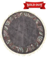 Full top-down view of the 5'3 x 5'3 Round Modern Nepal Rug showcasing its charcoal-gray wool field and hand-carved abstract border in olive, burgundy, and blue tones with light fringes.