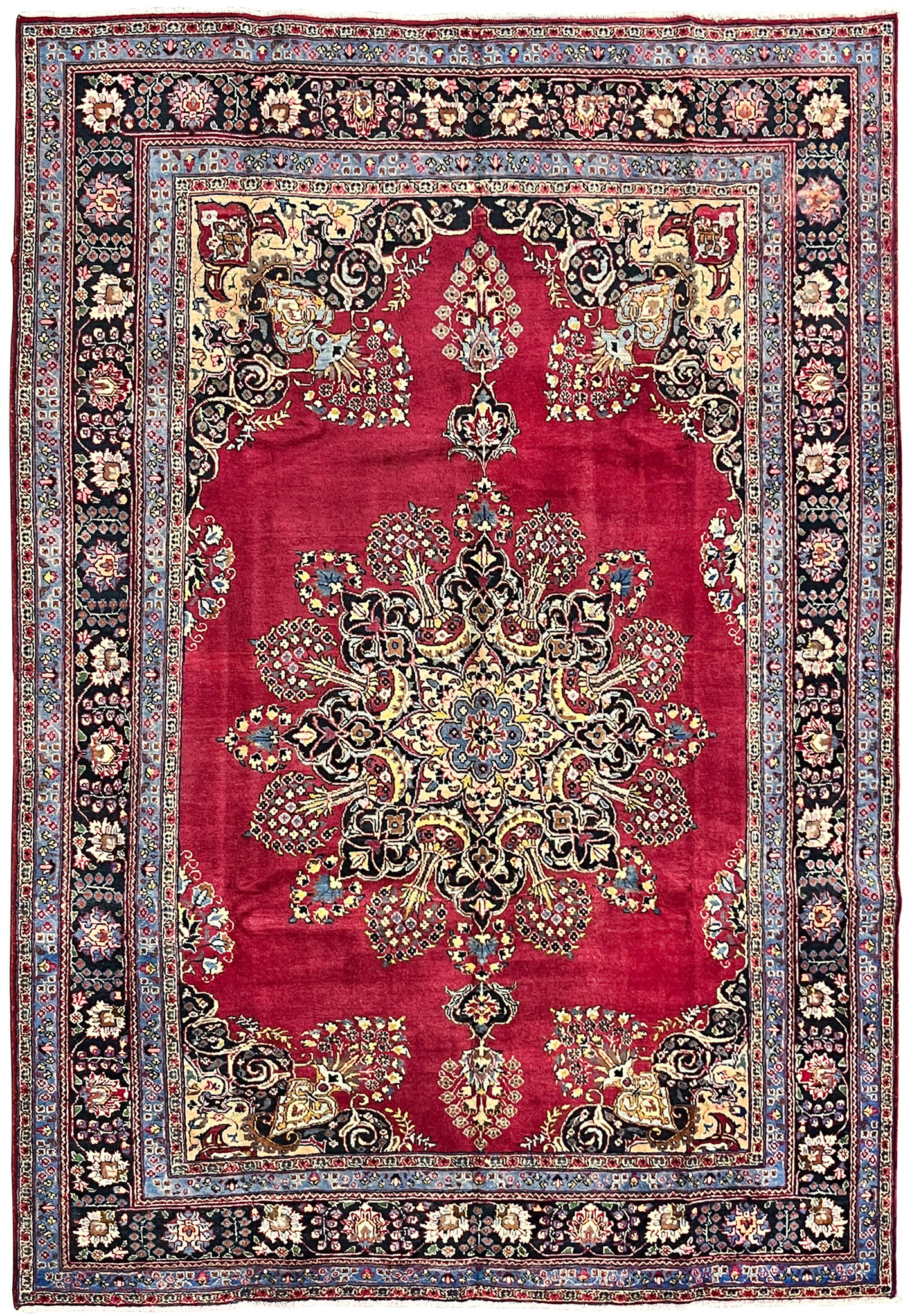 Full overhead view of Persian Kerman rug with crimson field, Lavar sunburst medallion, and navy main border