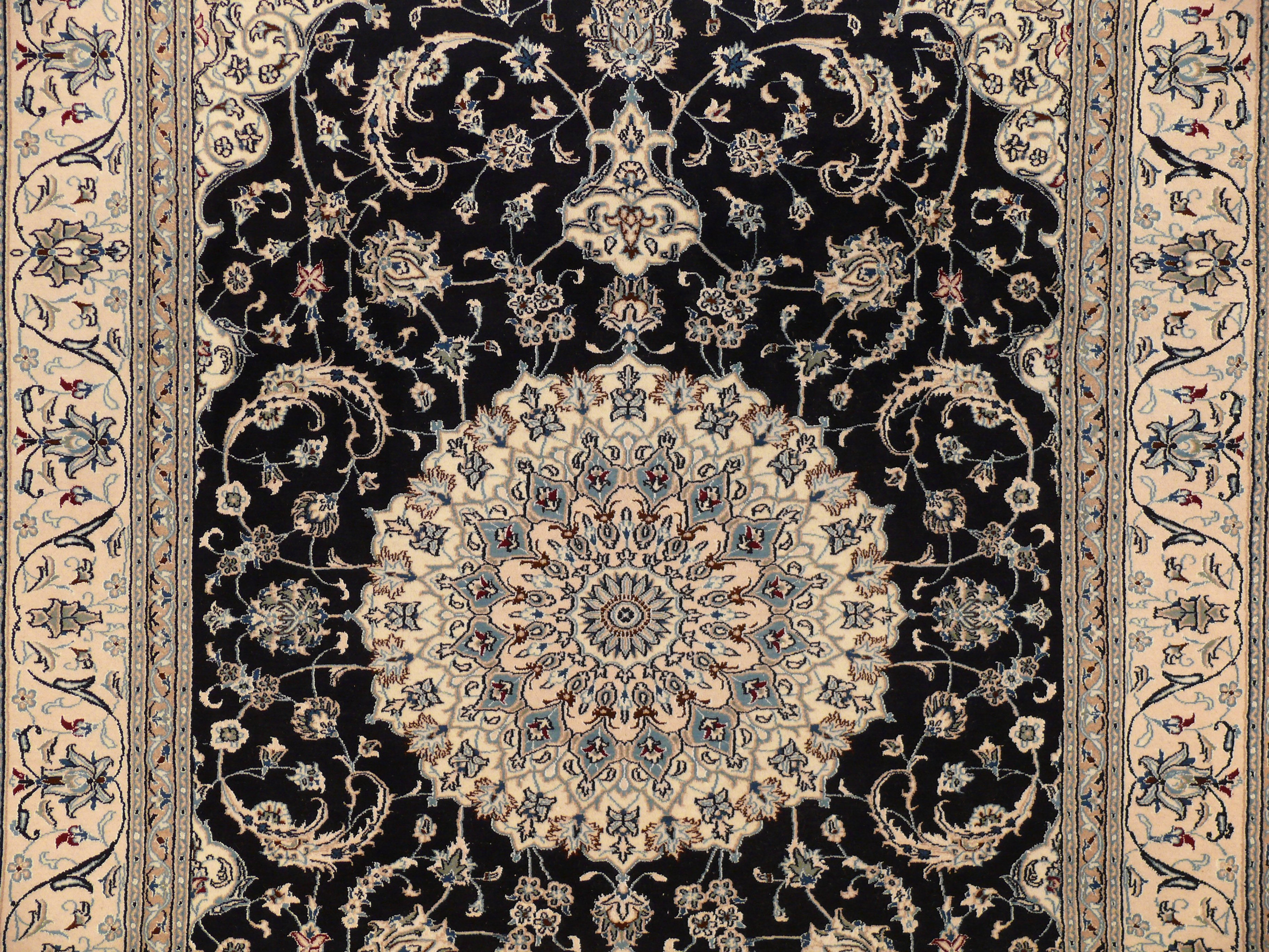 Close-up of medallion with navy center, ivory and sky blue outlines, wine red blossoms