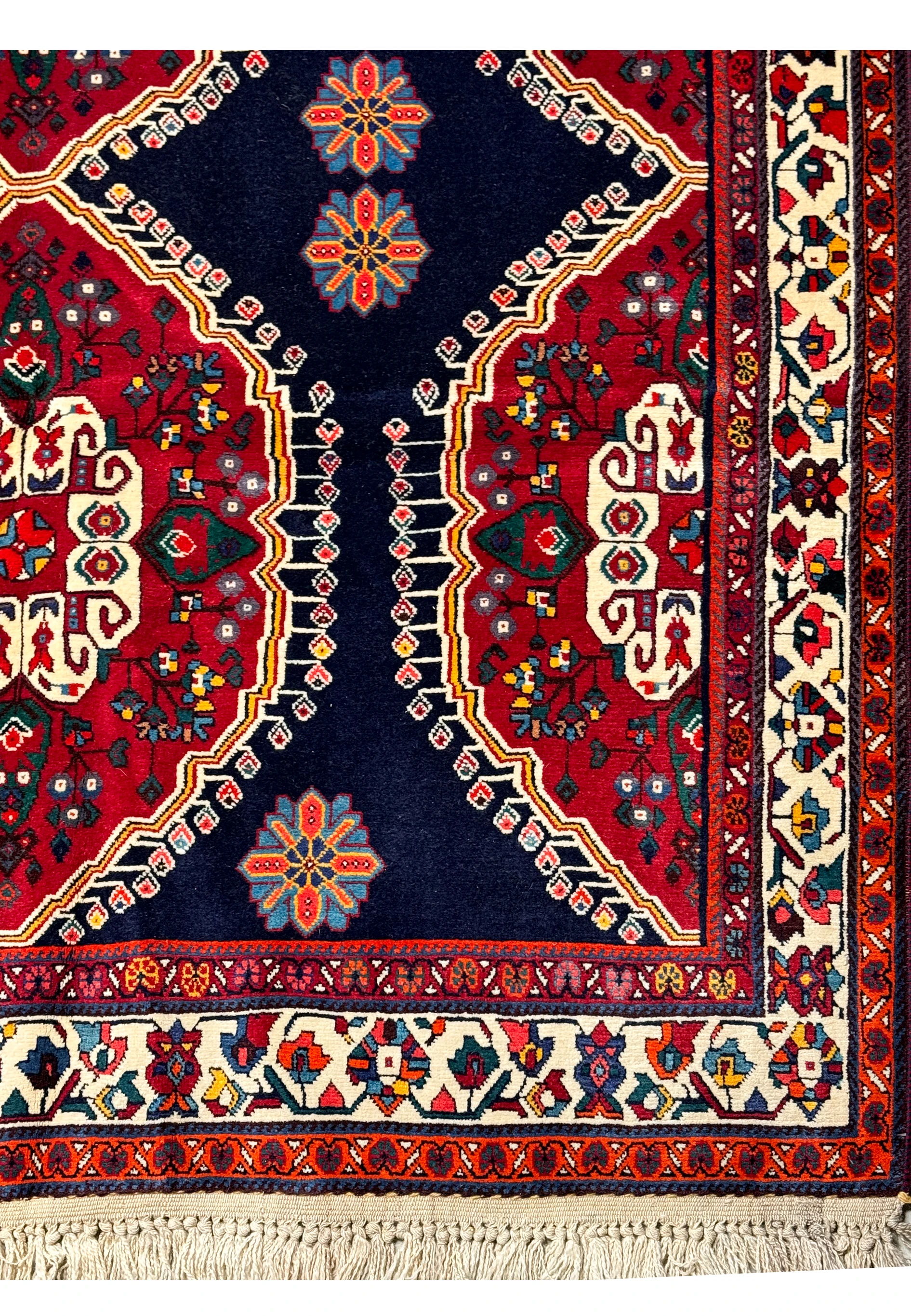 Detailed pattern of a Persian Qashqai rug showcasing the vibrant red medallions, blue backdrop, and a variety of floral and geometric shapes
