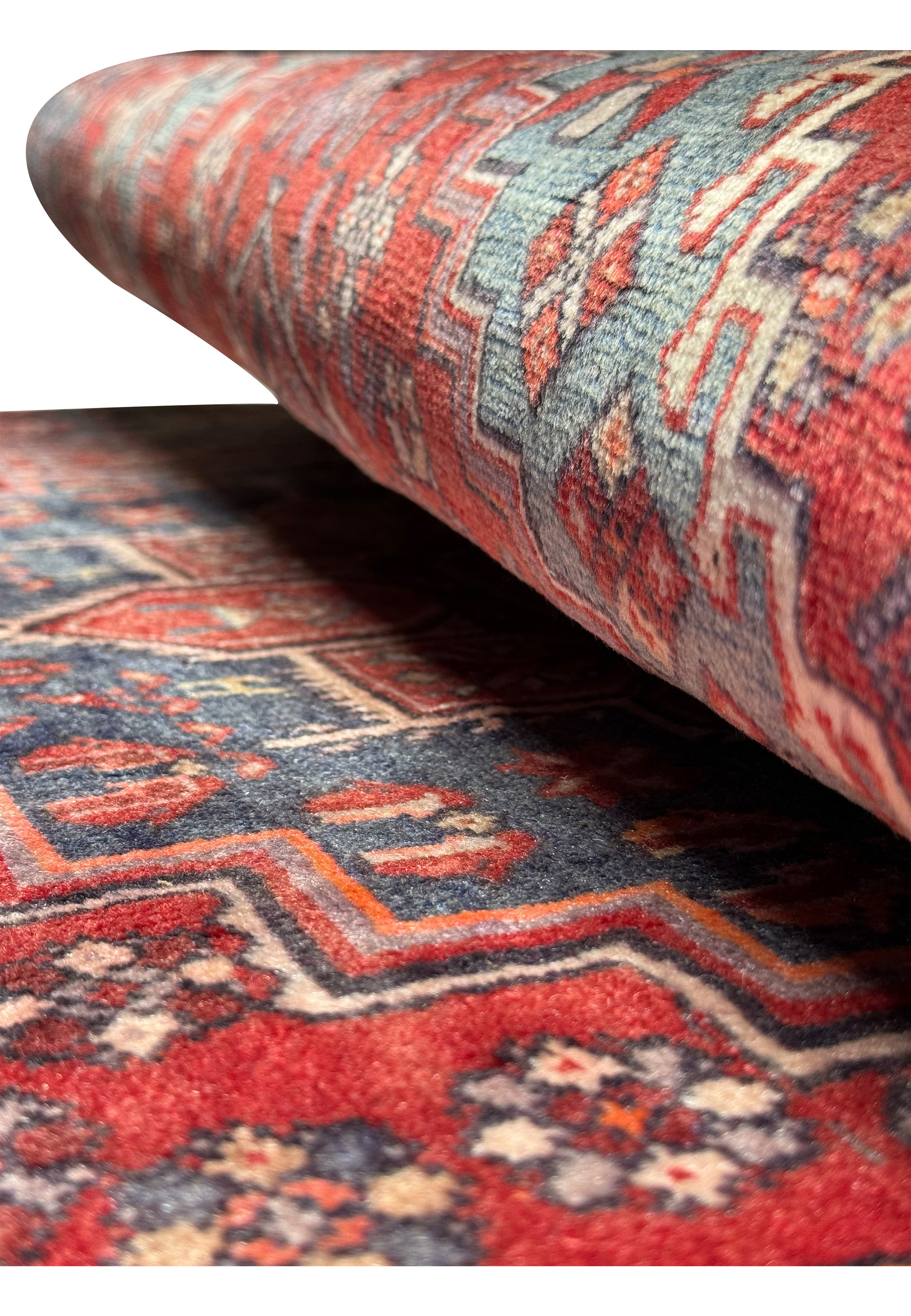 Side view of a rolled vintage Persian Bijar rug, highlighting the thickness and tight weave of the carpet, with a glimpse of the patterned design