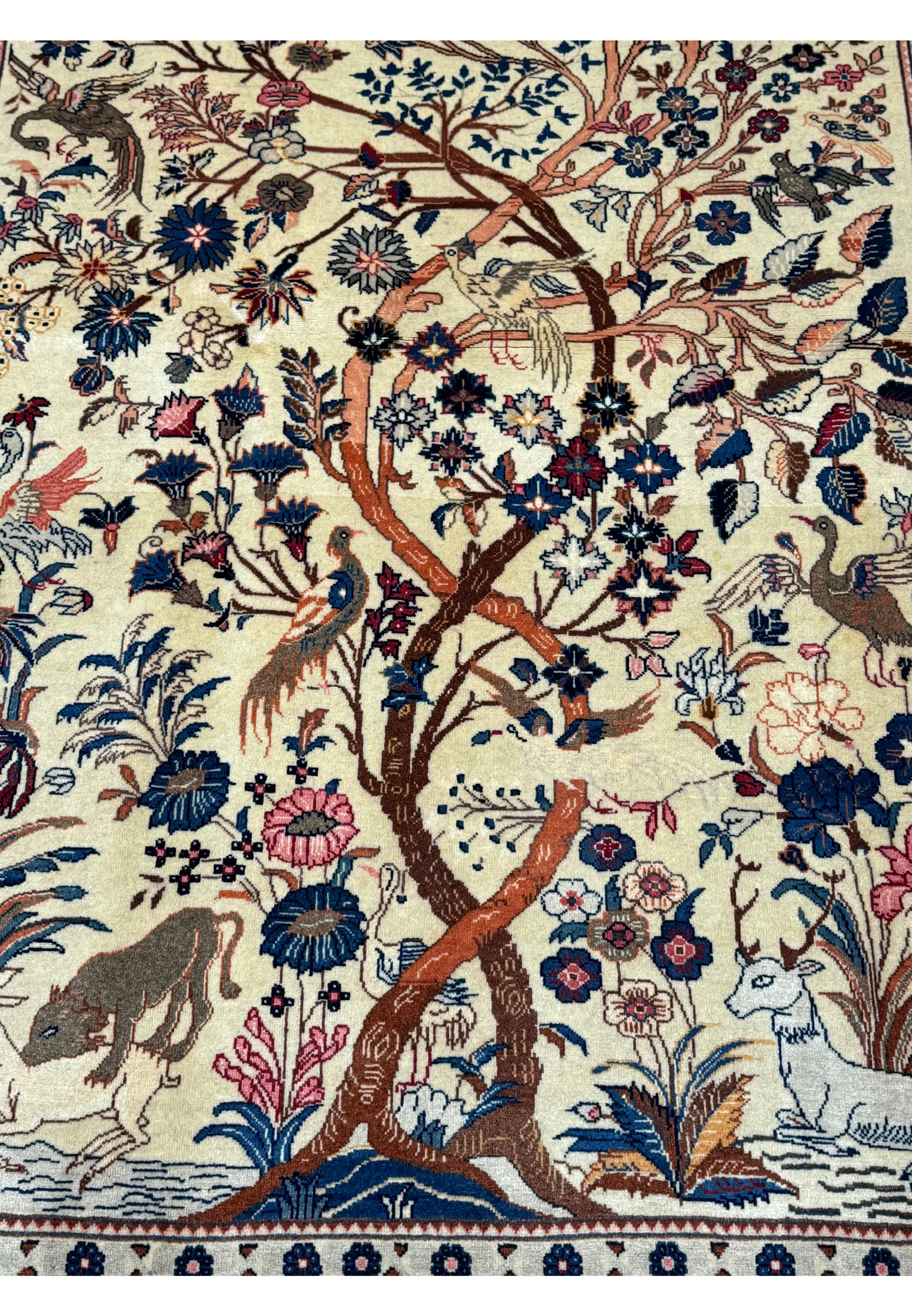 Close-up of the central Tree of Life design on an Antique Persian Kashan rug, highlighting the intertwined branches with birds and wildlife motifs on a cream background