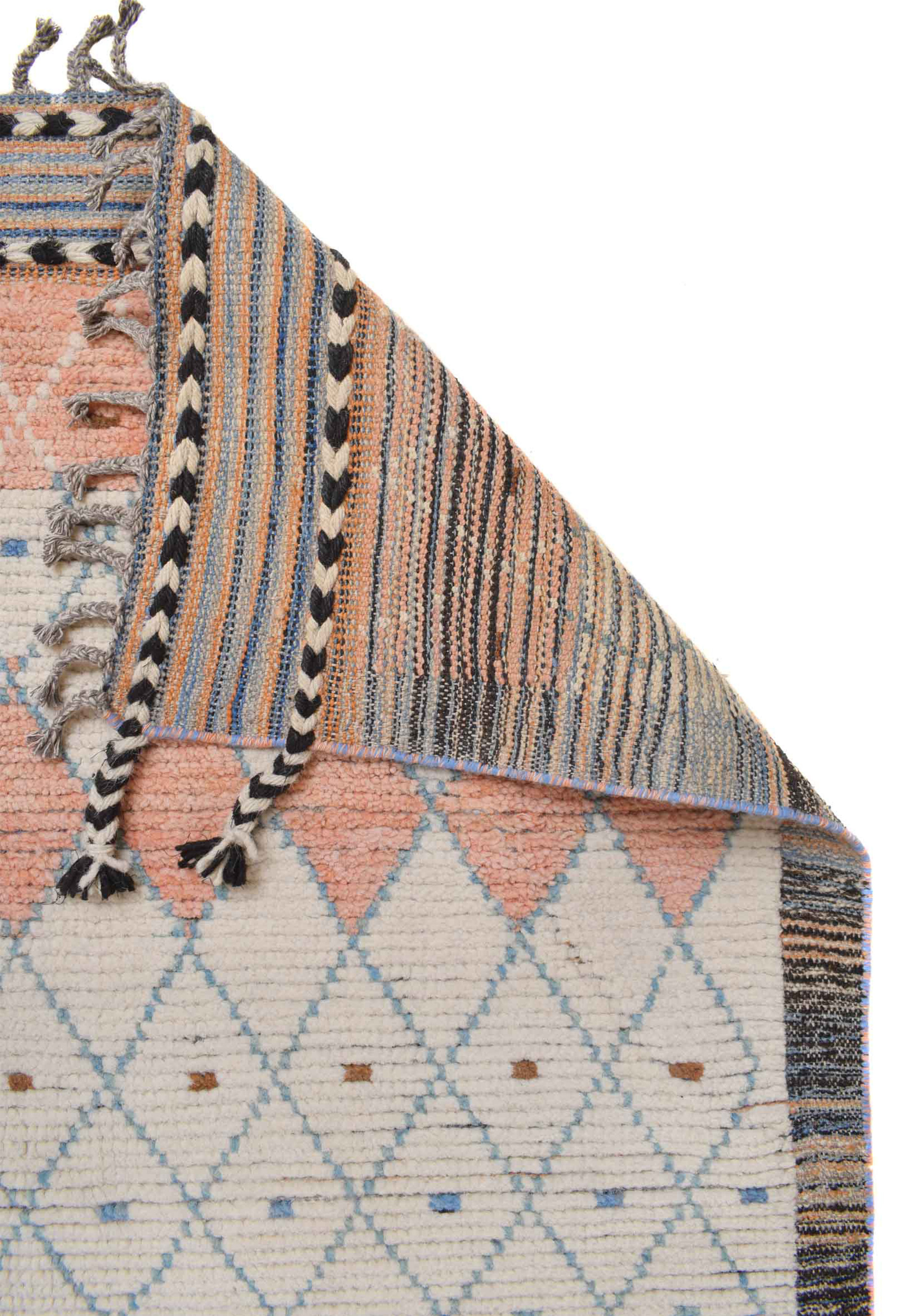 The corner of a modern Moroccan rug folded over to show the intricate pattern work and texture