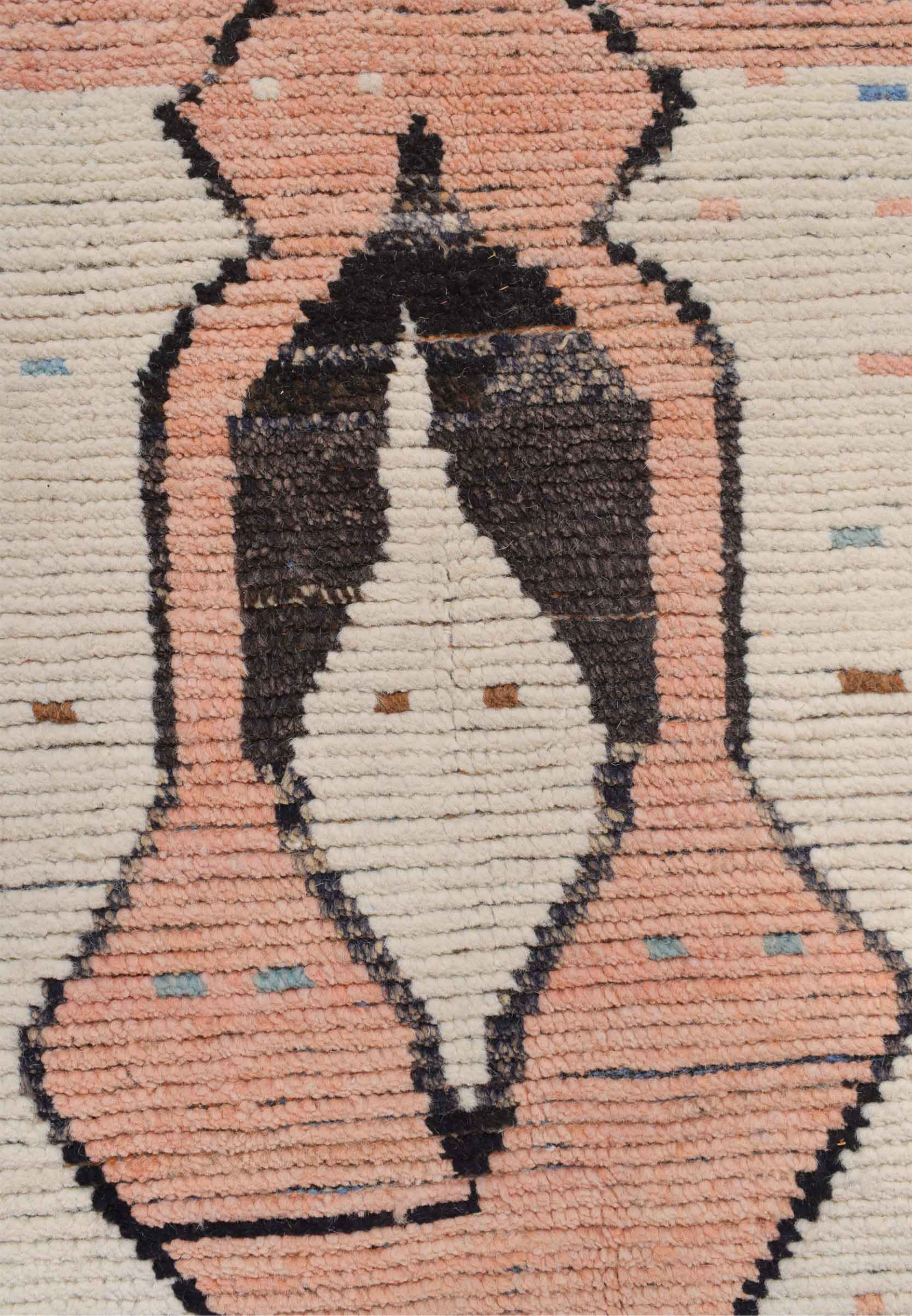 Detailed view of a diamond motif on a modern Moroccan rug, with a blend of peach, ivory, and black tones