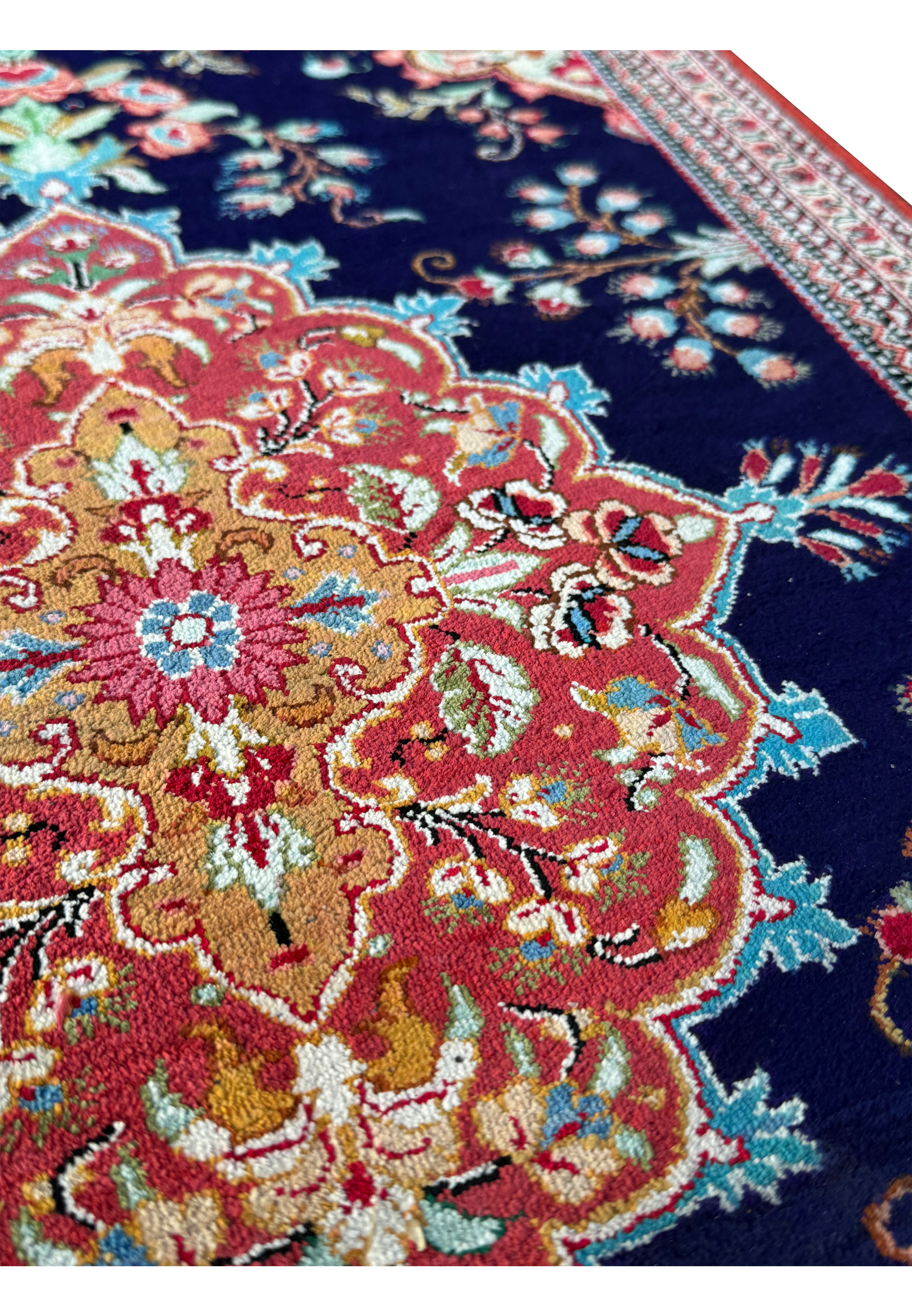 Angled view of a Persian Qum silk rug, emphasizing the depth of color and precision of the handwoven patterns