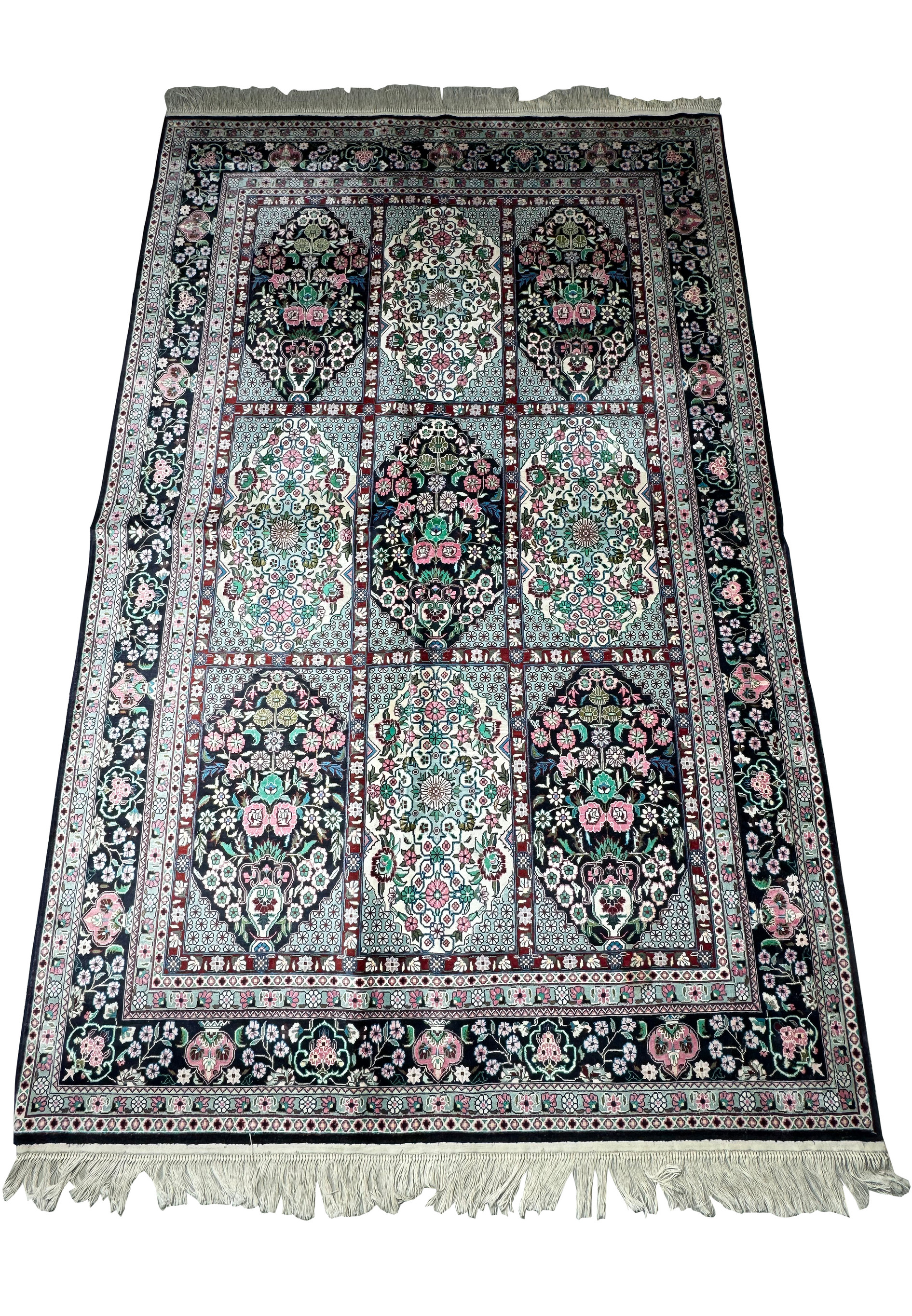 Full view of a Persian Qum silk rug displaying detailed floral designs and a rich color palette on a navy base