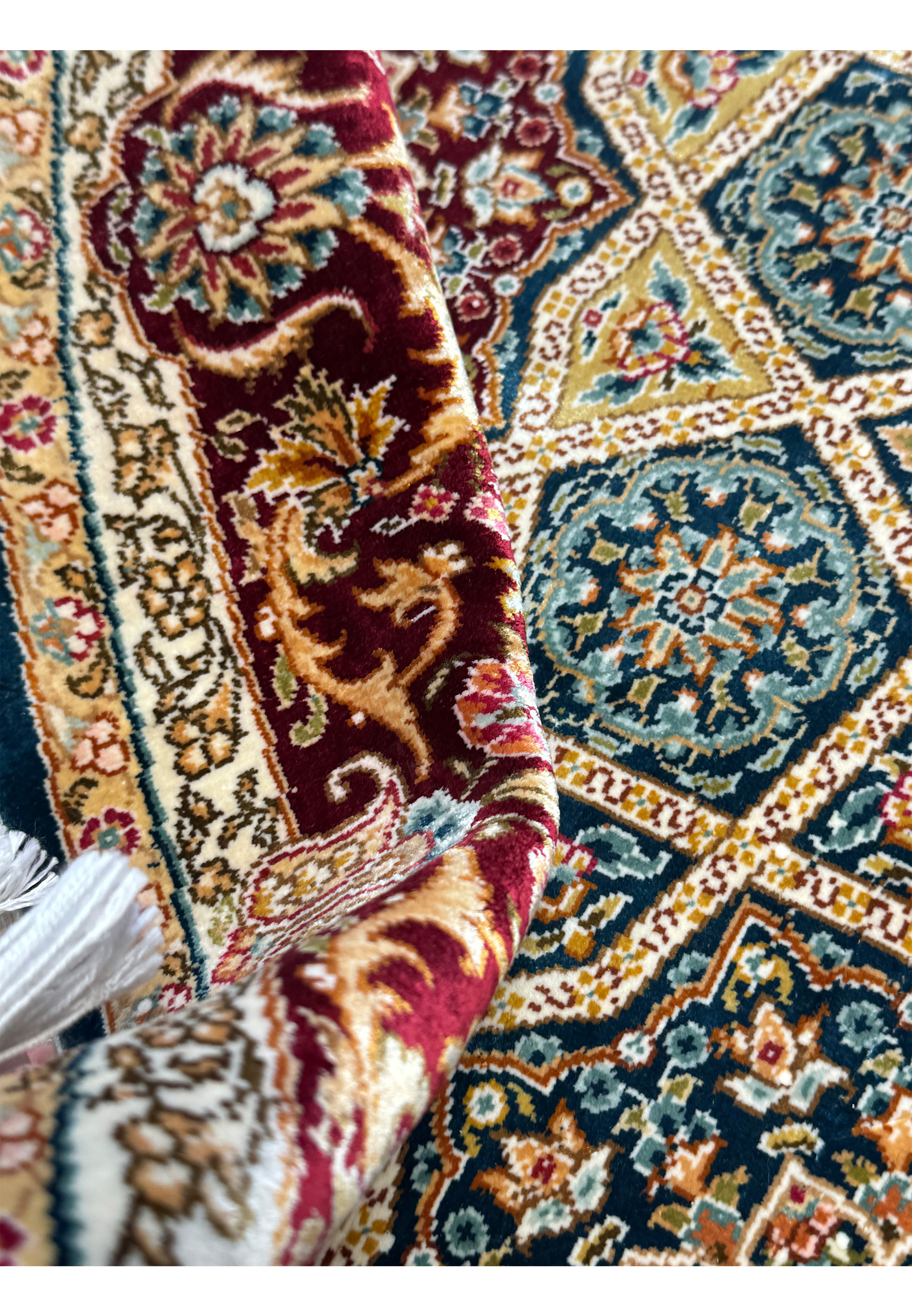 Edge view of the rolled Persian Qum silk rug, highlighting the compact weave and the rug's thickness