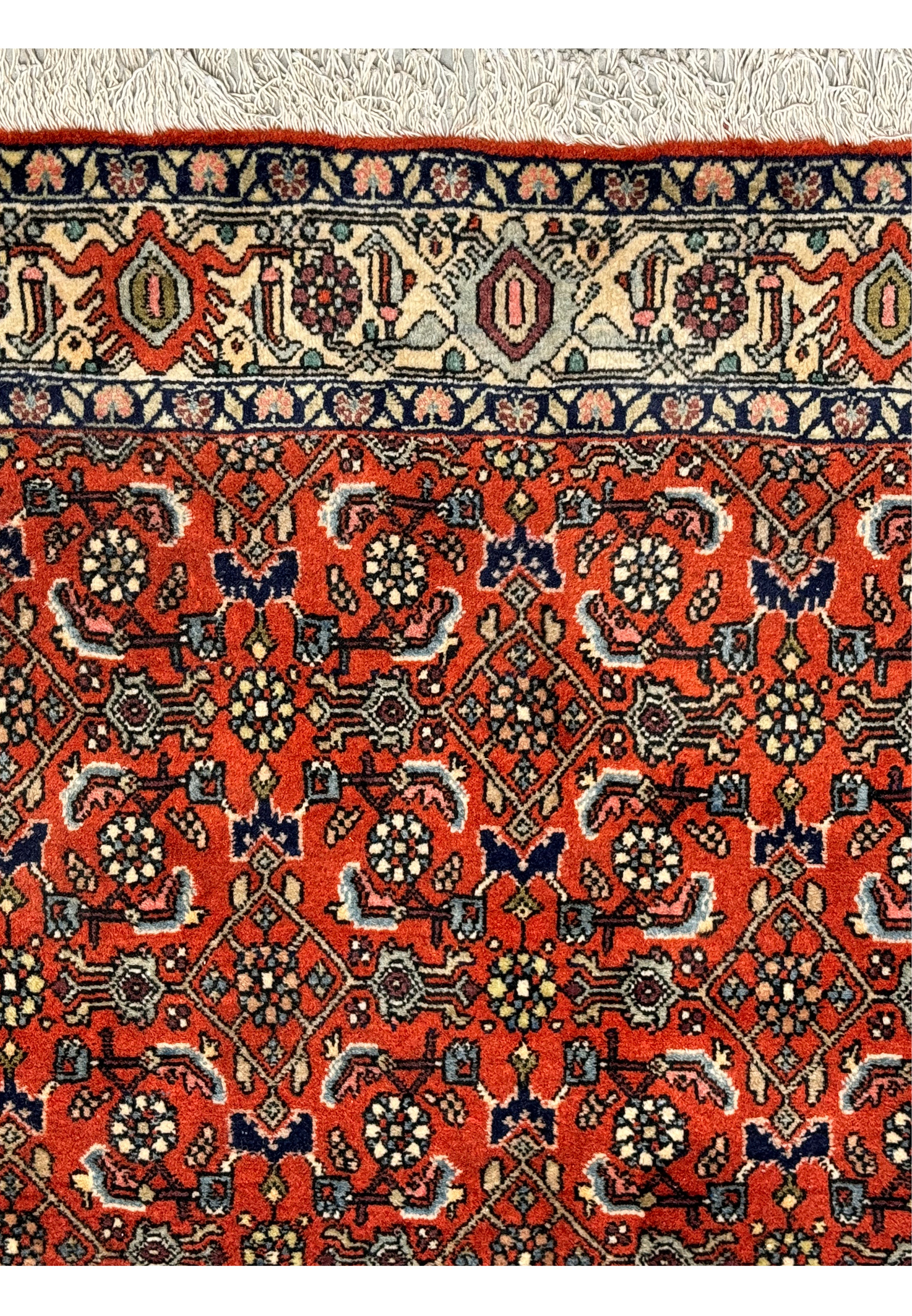 A detailed view of the Bijar rug, focusing on the complex interaction of red, indigo, and cream patterns.