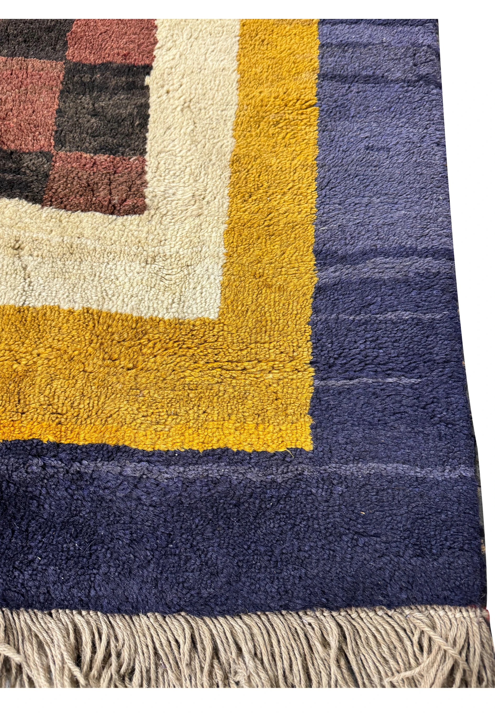 Close-up of the modern Nepal rug's edge, displaying the luxurious golden yellow and indigo border against the plush checkerboard pattern.