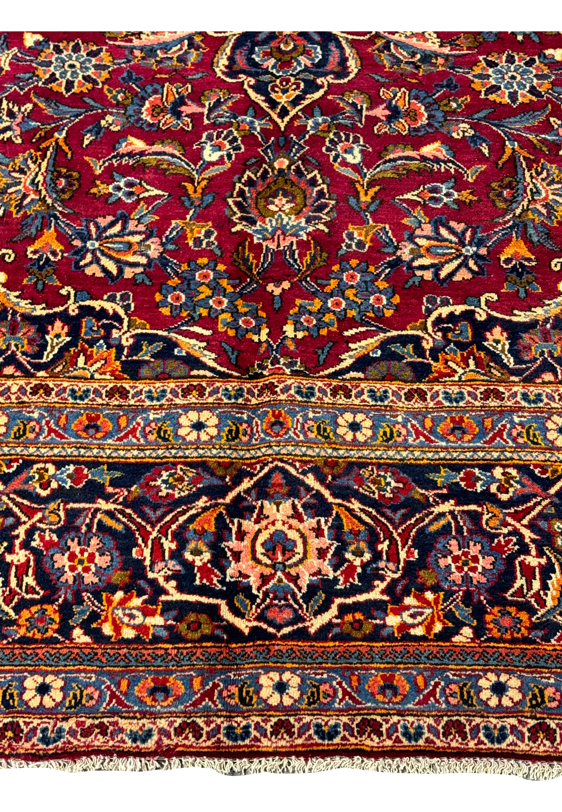 Corner detail of the Persian Kashan rug, where the opulent border meets the vibrant, patterned field.