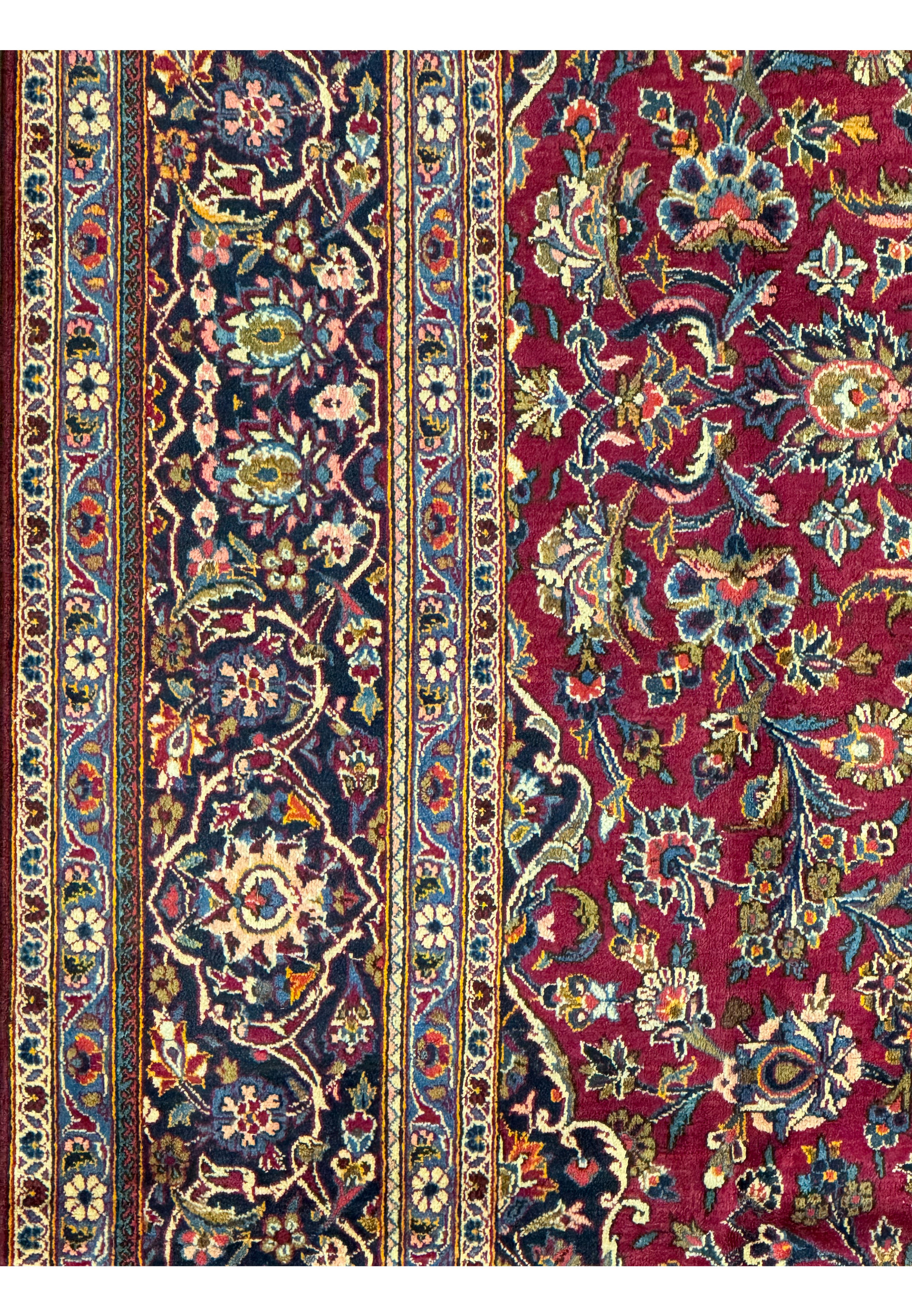 Detailed section of a Persian Kashan rug showing the exquisite border design with floral and geometric motifs.