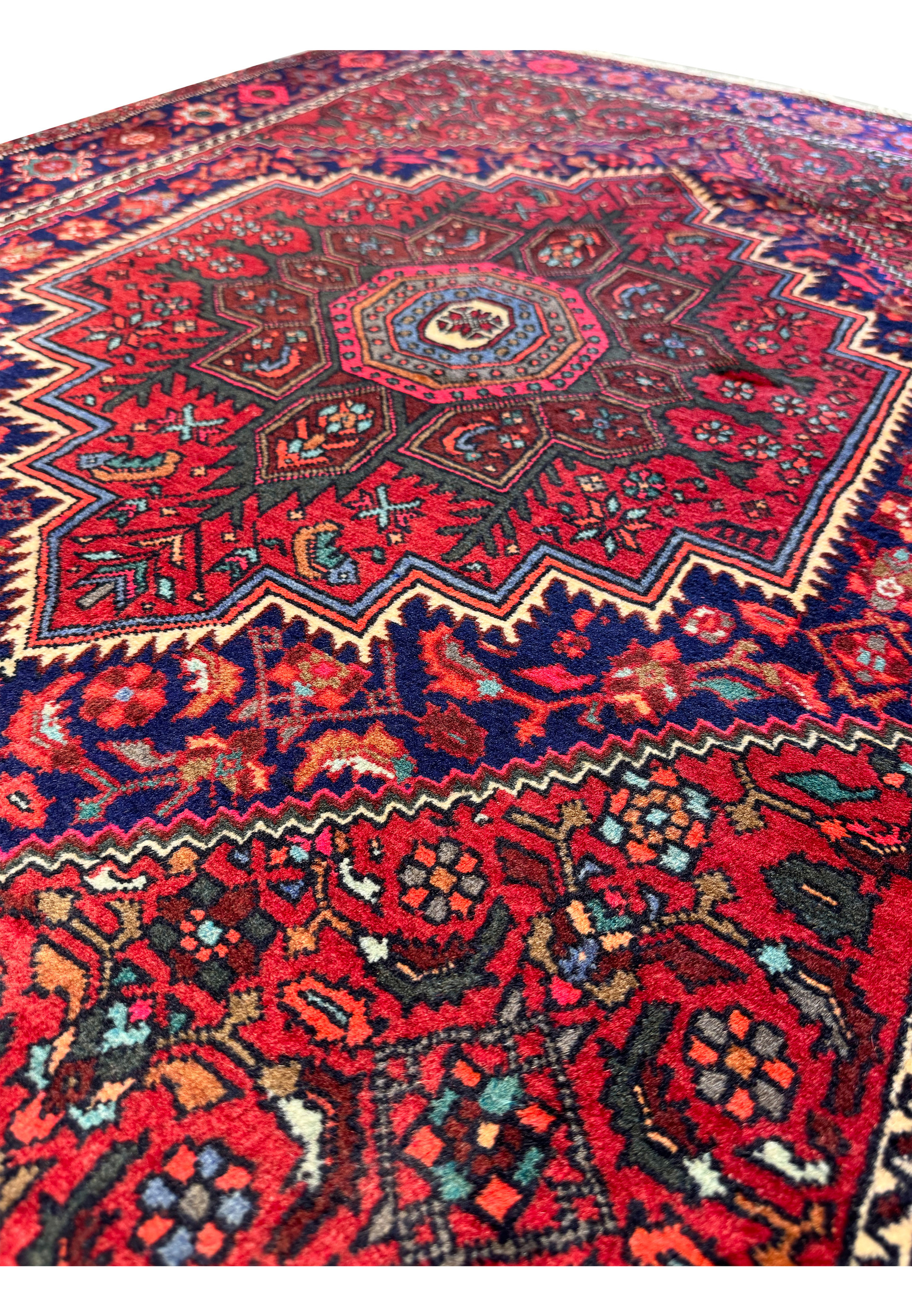 Angled view of a rolled 3'4" x 4'8" Persian Gholtogh rug, emphasizing the thickness and plush pile
