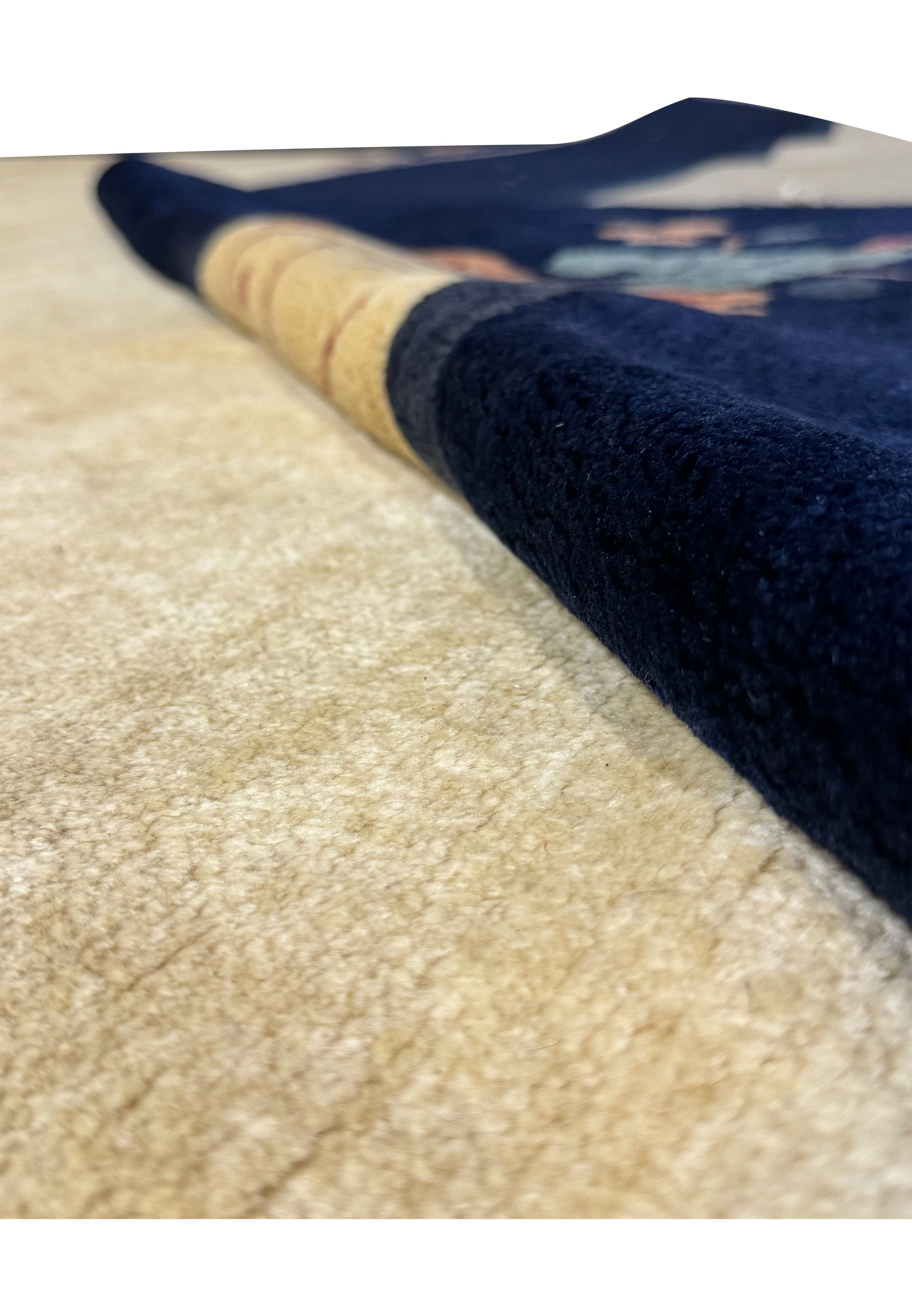 Diagonal view of the vintage Art Deco rug's navy blue border meeting the beige center, adorned with floral patterns