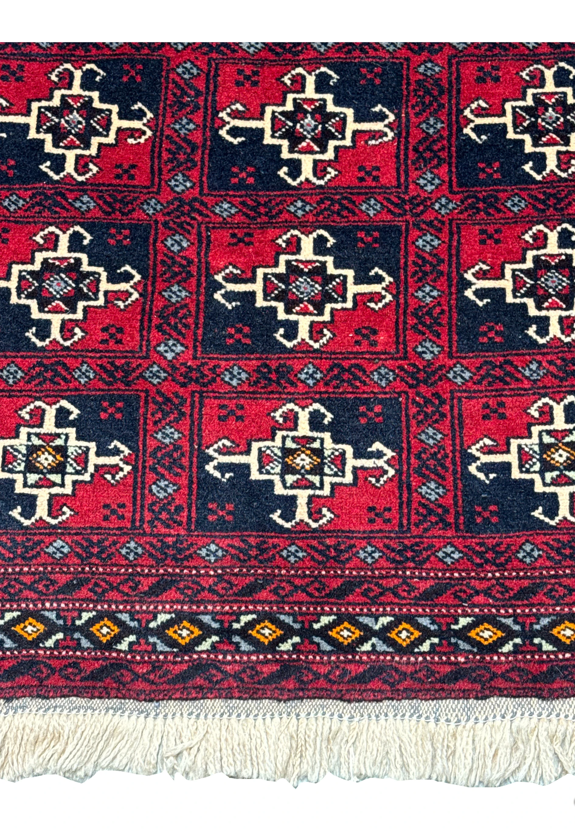 Top section of the Persian Baluch Rug, highlighting the intricate border designs and the fringed edge.