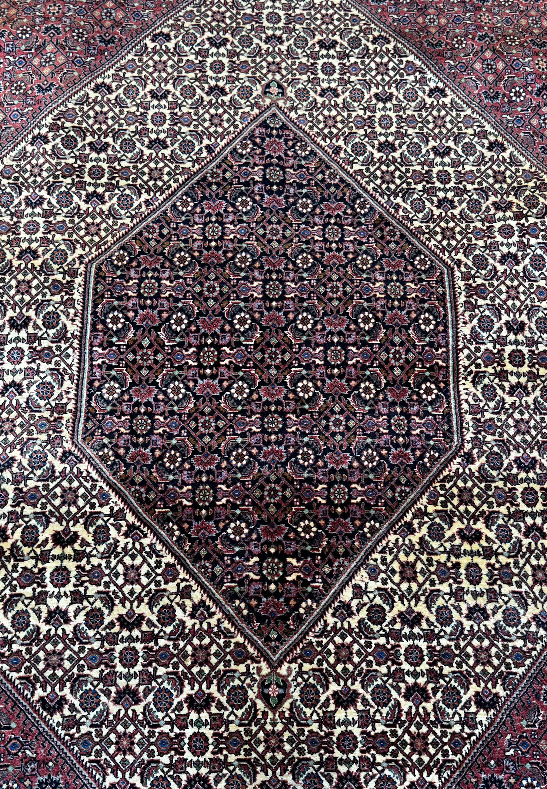 An overhead view of a Persian Bidjar rug, highlighting the central diamond medallion set against a detailed field of dark and light patterns