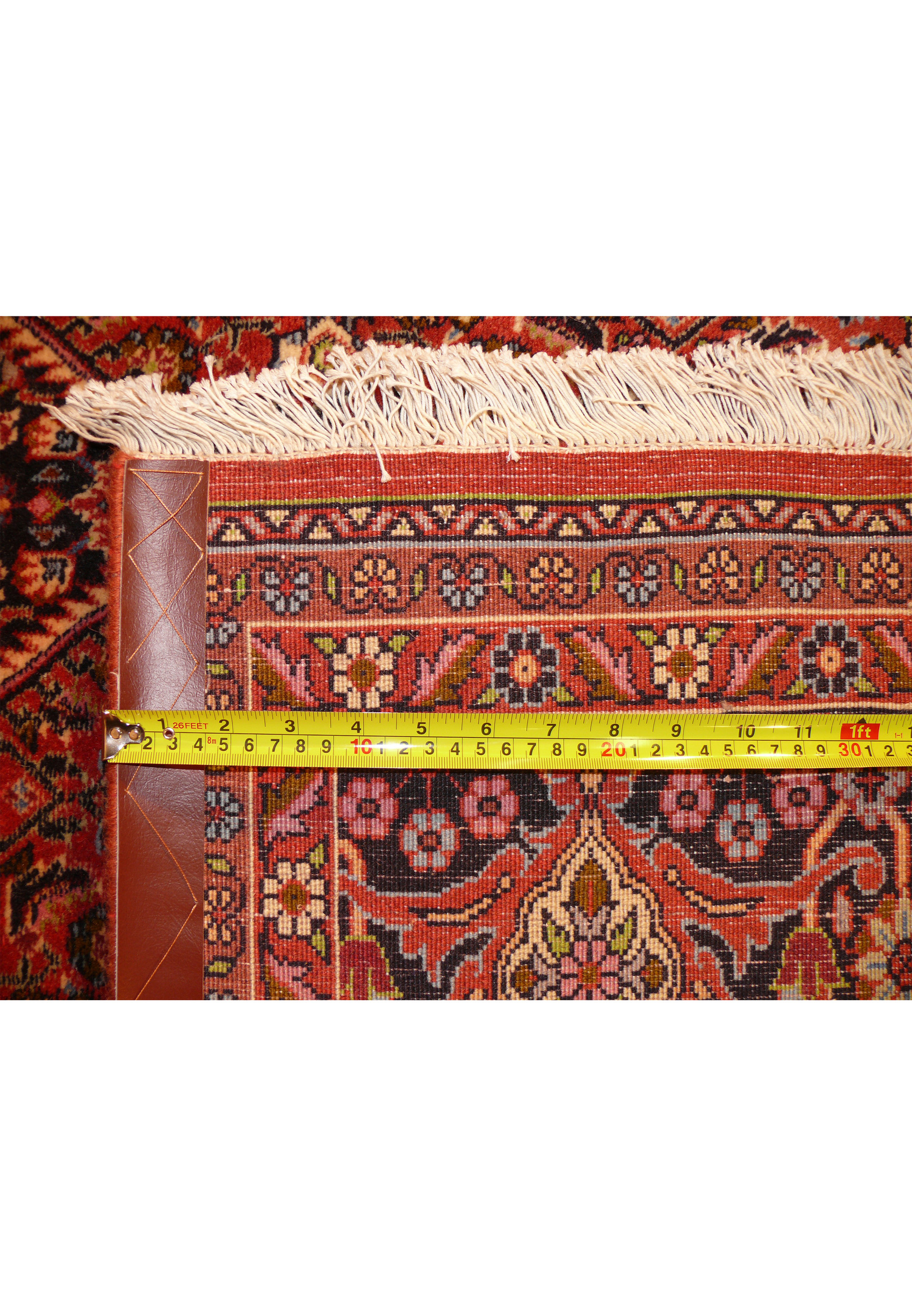 A measuring tape across the back of the Bijar rug, emphasizing the exceptional knot density per square inch, a hallmark of its exceptional craftsmanshi