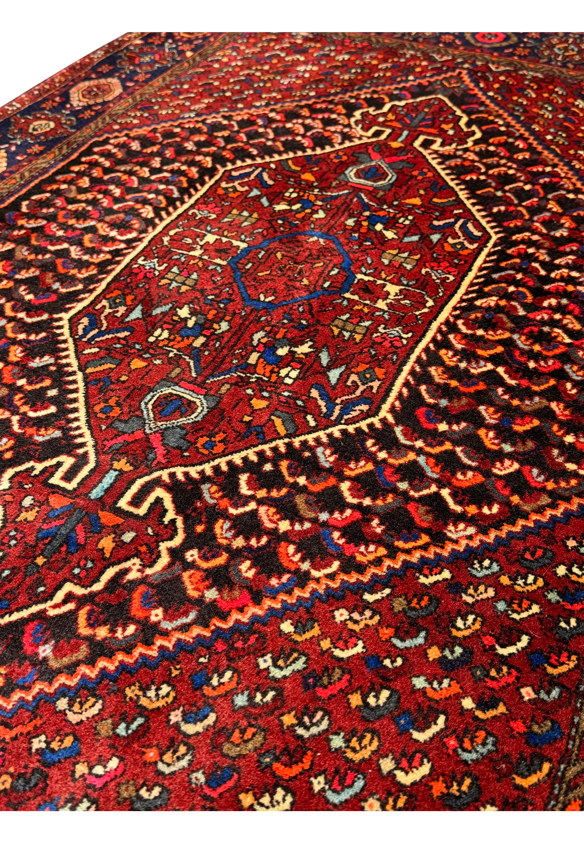 Edge and fringe detail of a Persian Gholtogh rug, highlighting the precision of the border patterns in navy blue and red, with delicate floral accents