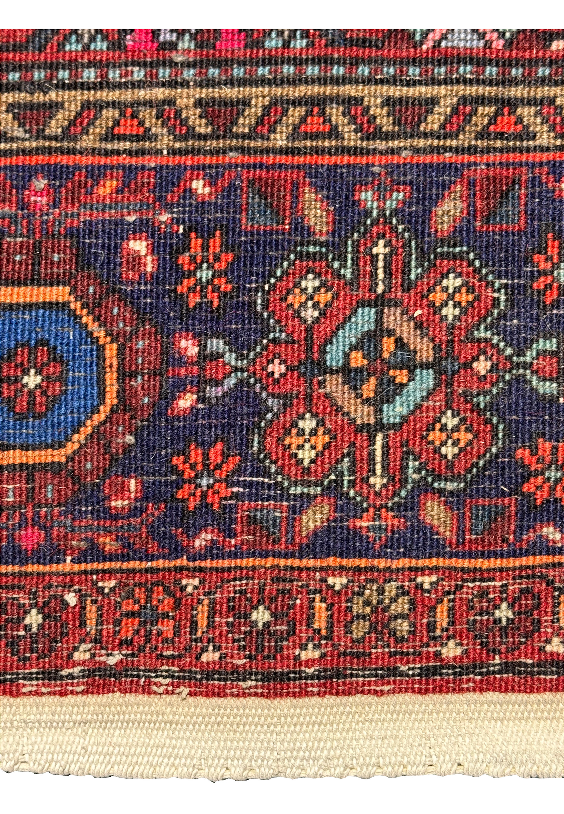 Close-up of the backside and fringe of a Persian Gholtogh rug, showing detailed patterns and color variations in red, blue, ivory, and hints of orange and green and weave density.