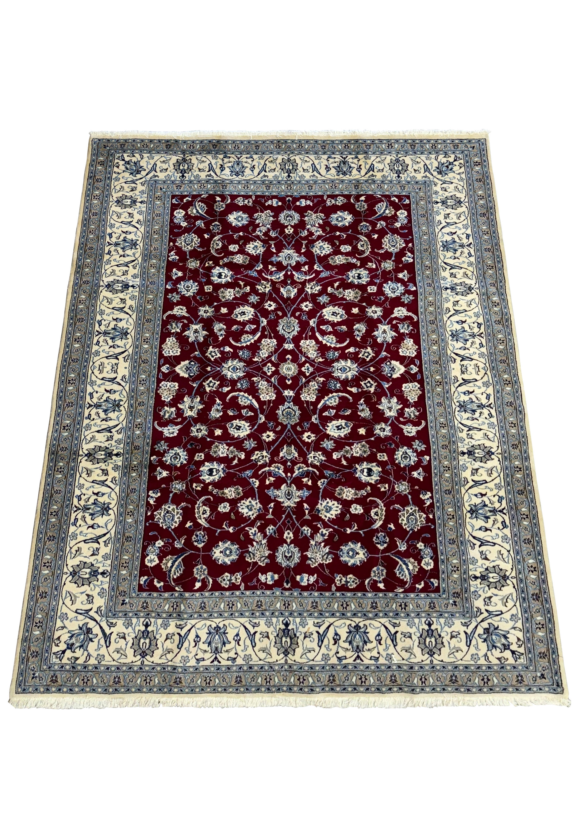 Full view of a Persian Nain 9La rug on the floor, showing the rich red center surrounded by ornate borders in cream and blue, emphasizing the rug's luxurious wool and silk blend